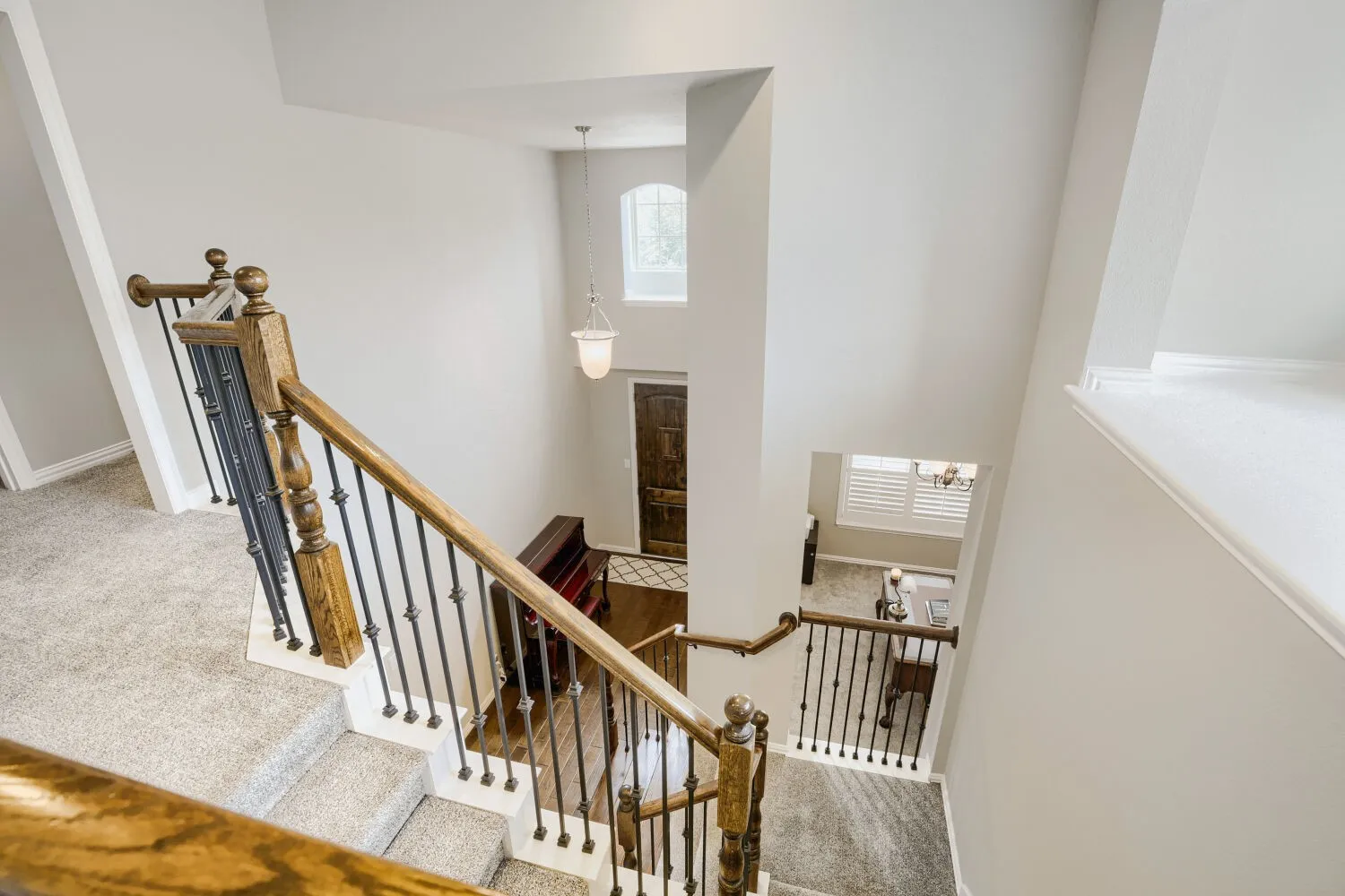 Staircase featuring wood handrails, decorative iron balusters, and light-toned carpeting