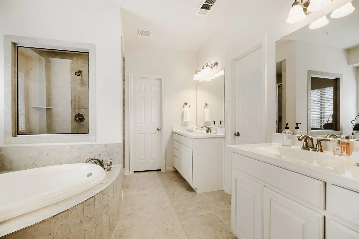 Bathroom featuring a built-in soaking tub, tiled shower with glass enclosure, dual vanity sinks, and tile flooring