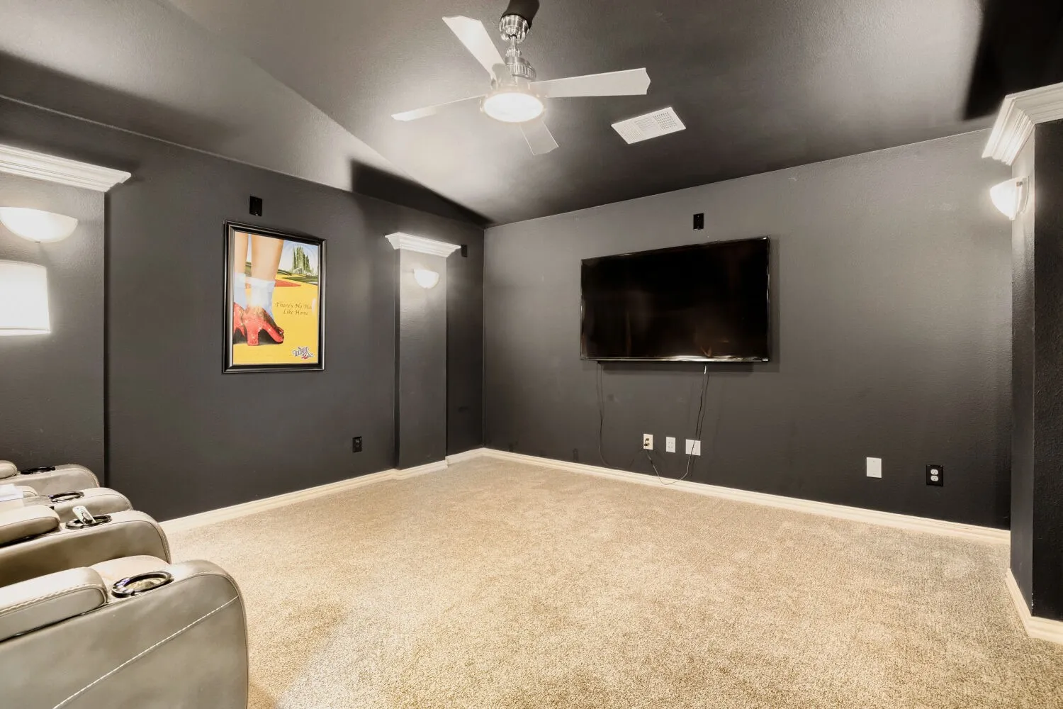 Dedicated media room featuring dark walls, recessed lighting, wall sconces, a ceiling fan, and carpet flooring
