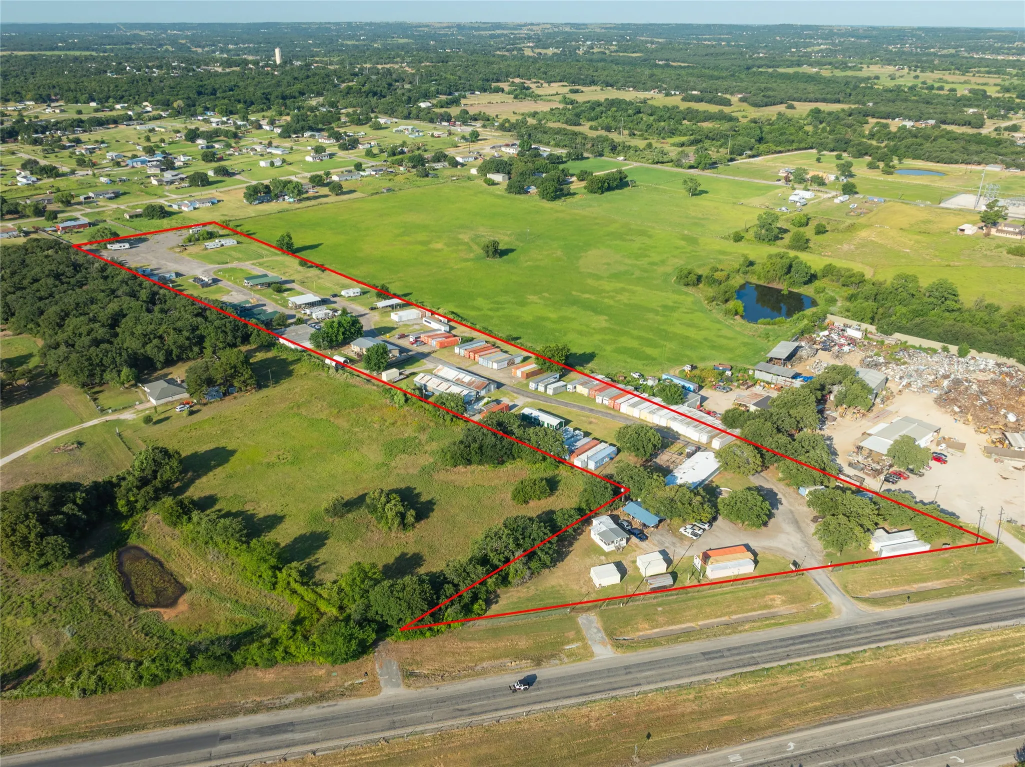 Expansive land parcel featuring open fields, wooded areas, and a visible pond