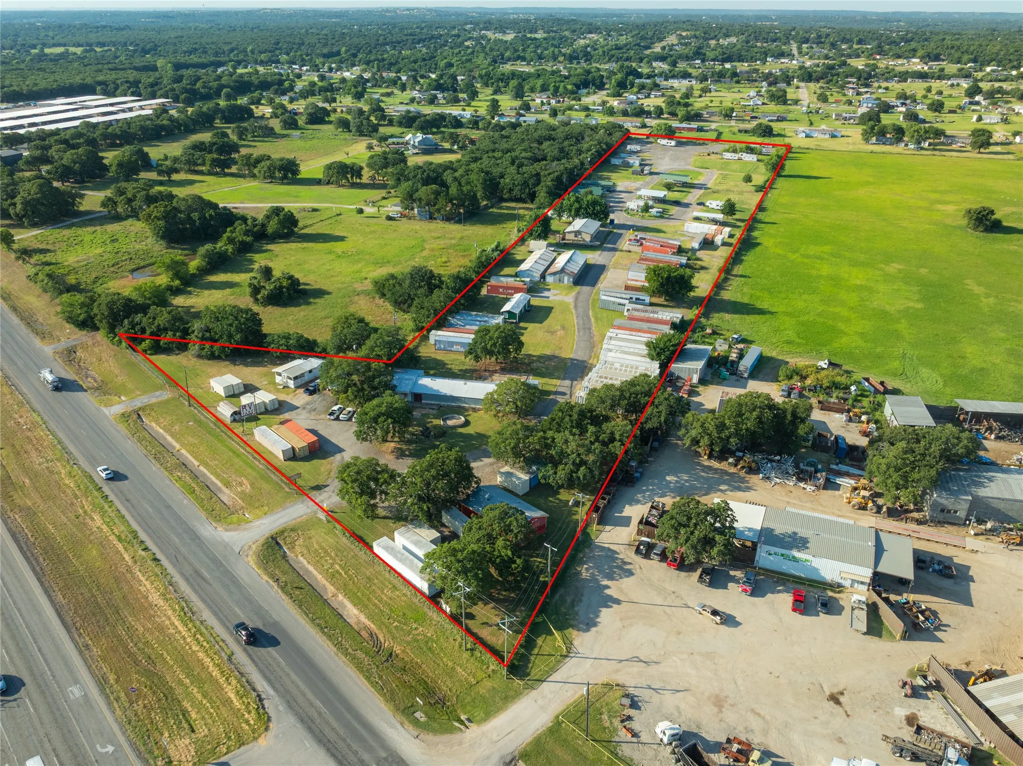 Expansive parcel featuring multiple outbuildings, mature trees, and a direct frontage to a multi-lane roadway