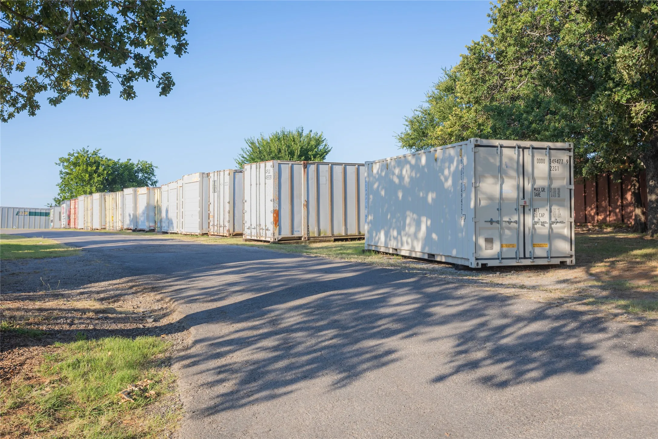 Row of white storage containers positioned on a gravel and paved surface