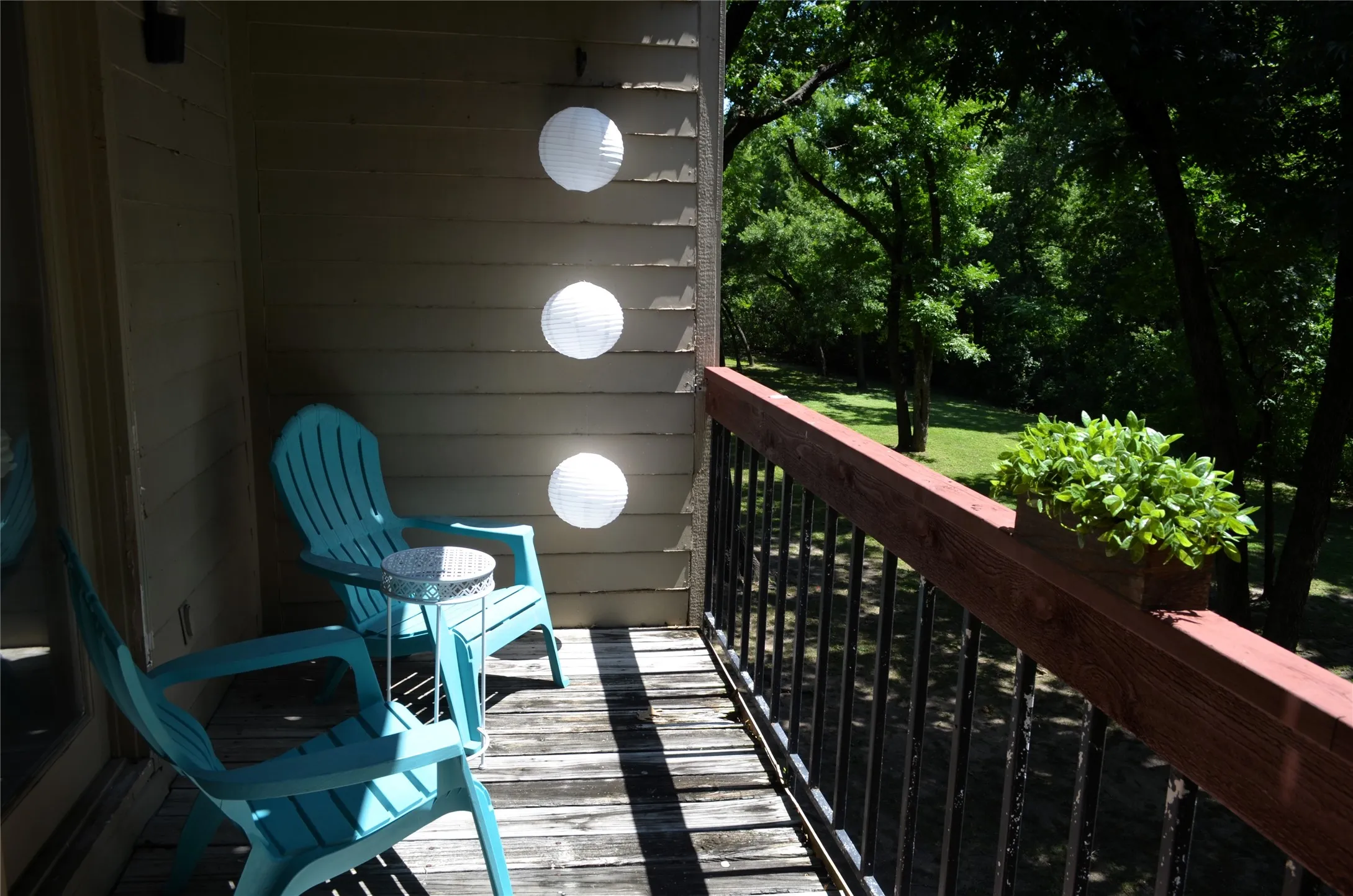Private balcony featuring wood-finish decking and a dark wood railing with black spindles