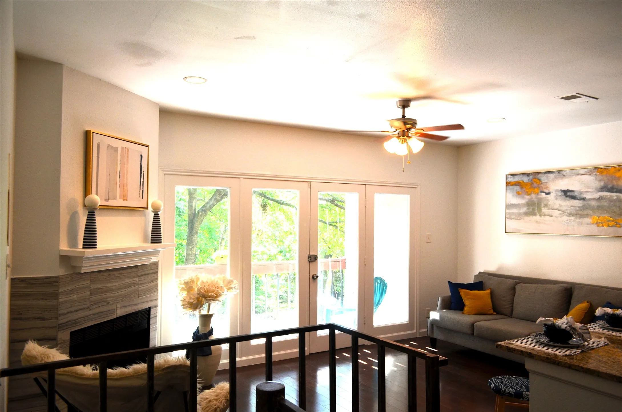 Spacious living area featuring dark wood-finish flooring, a contemporary fireplace with tile surround, and direct access to an outdoor area through a set of double French doors