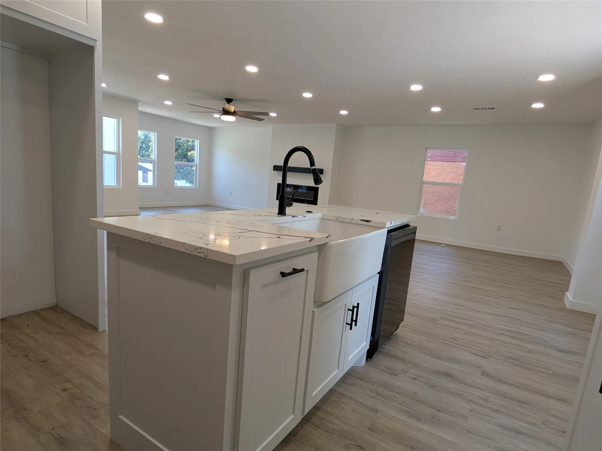 Kitchen island with a farmhouse sink and matte black faucet, featuring a light-toned countertop with veining