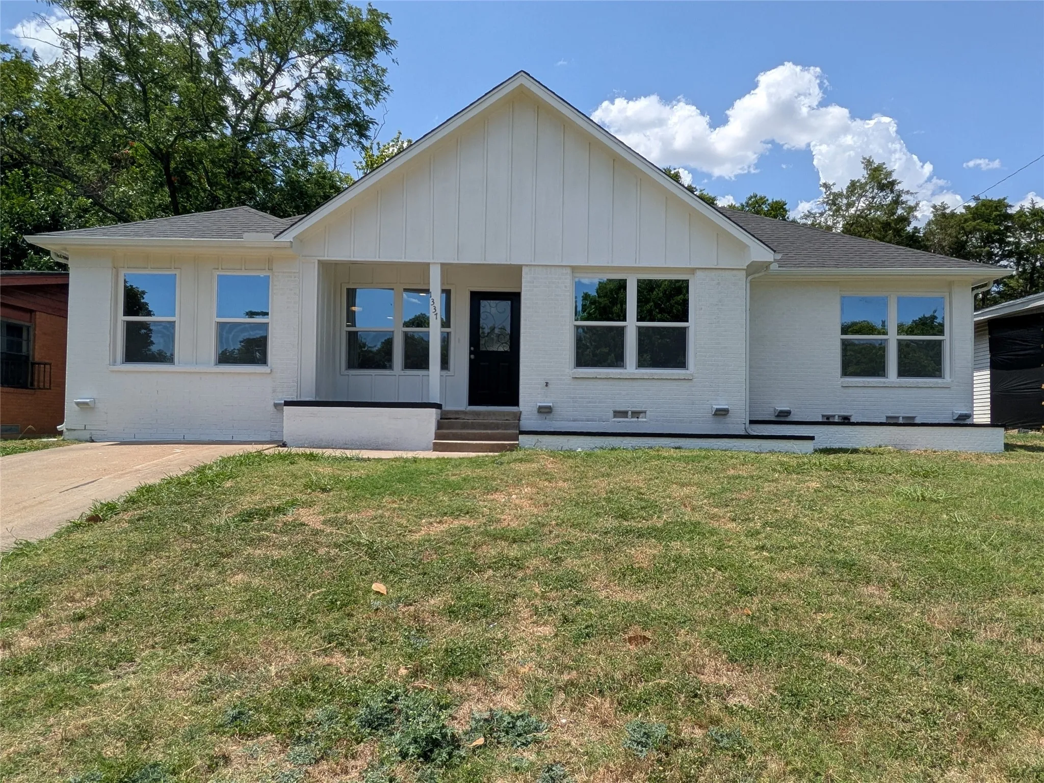 White brick exterior with a board and batten gable accent
