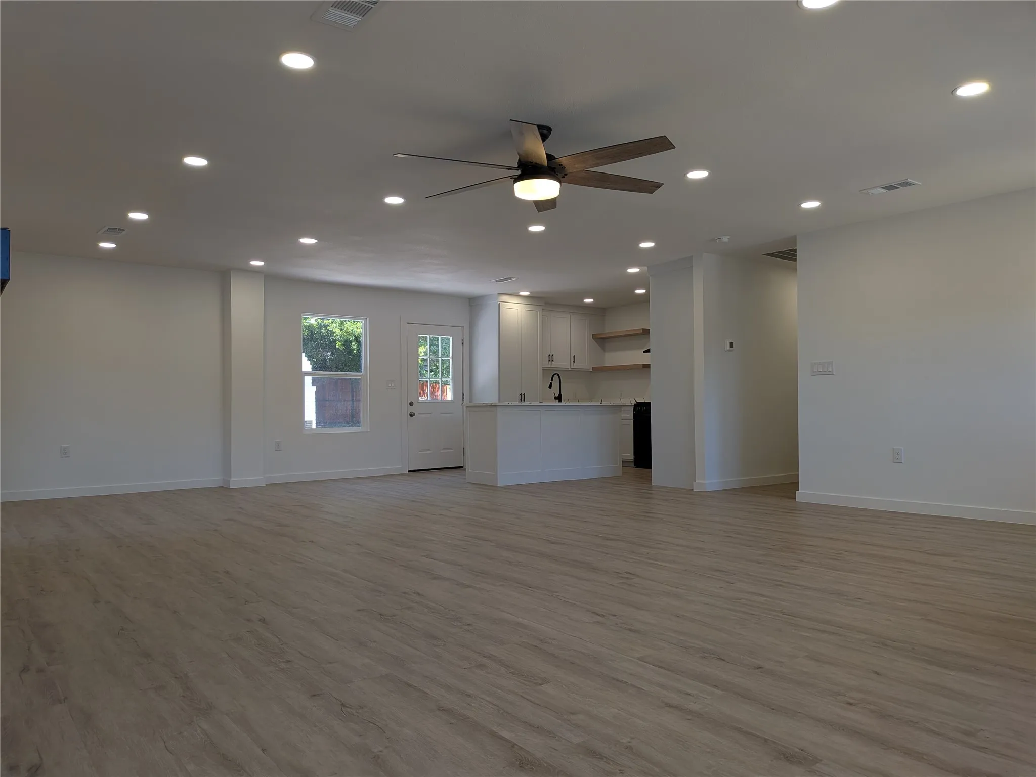 Open-concept living area featuring light wood-finish flooring, recessed lighting, and a ceiling fan