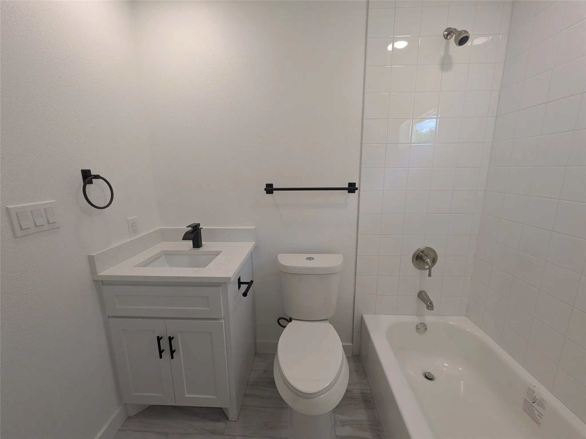 Contemporary bathroom featuring a white vanity with a quartz countertop, black hardware, and a single-handle faucet