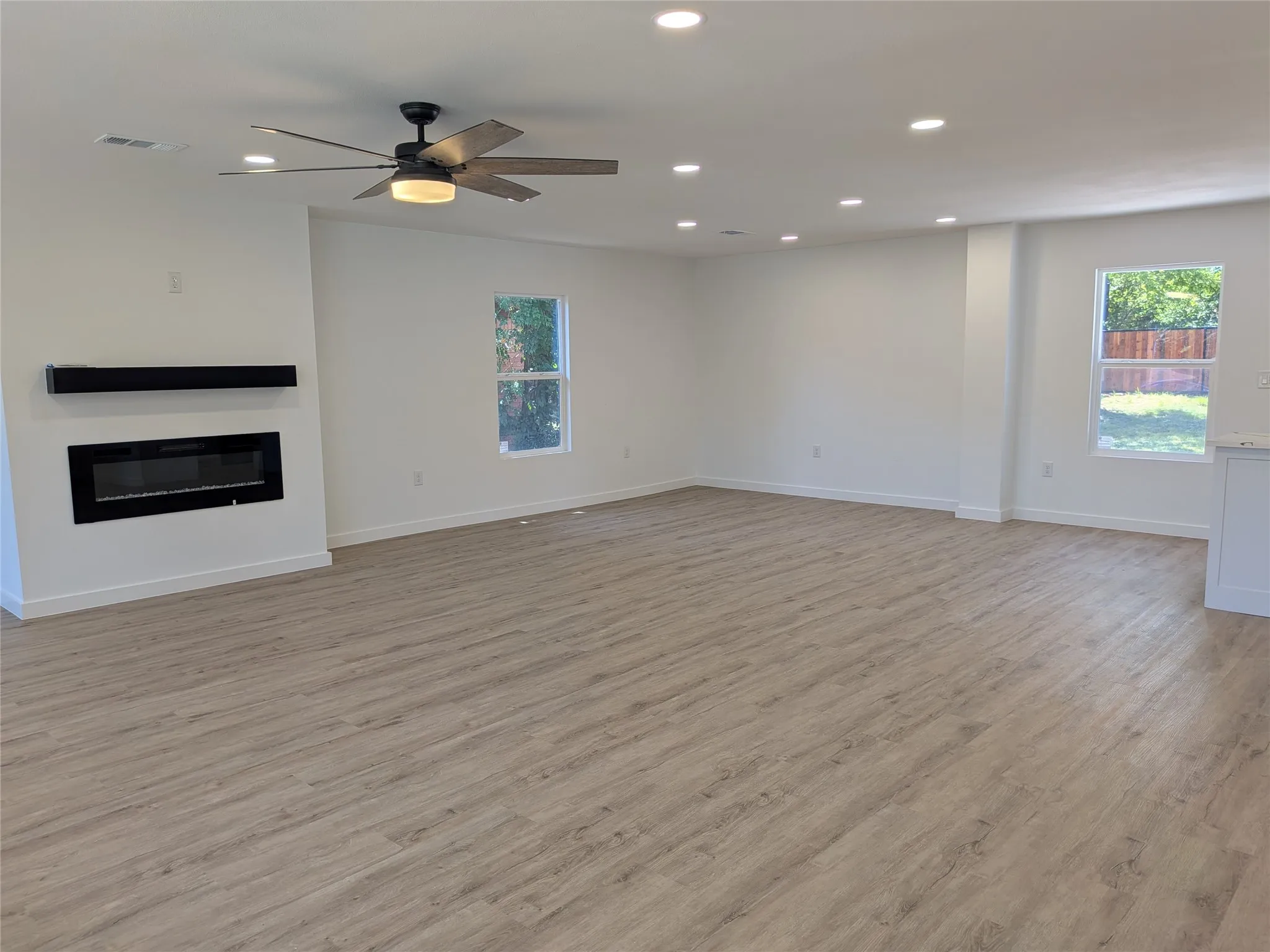 Expansive living area featuring light wood-finish flooring, recessed lighting, and a modern ceiling fan