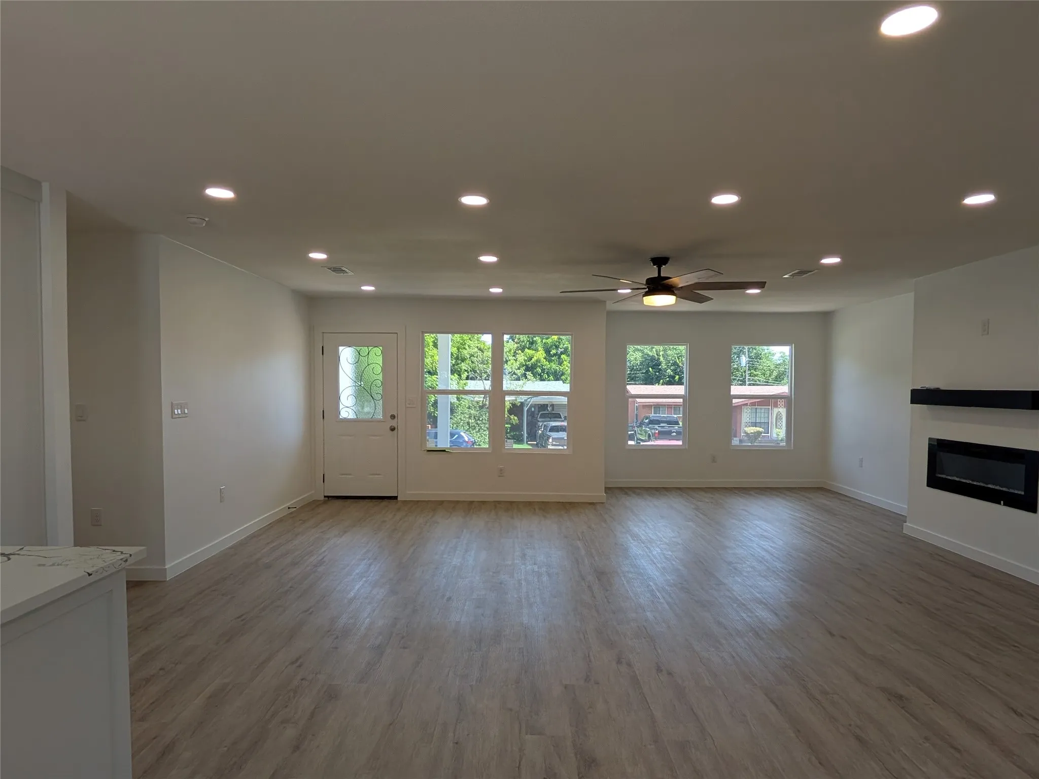 Spacious interior featuring wood-finish flooring, a contemporary fireplace, and recessed lighting