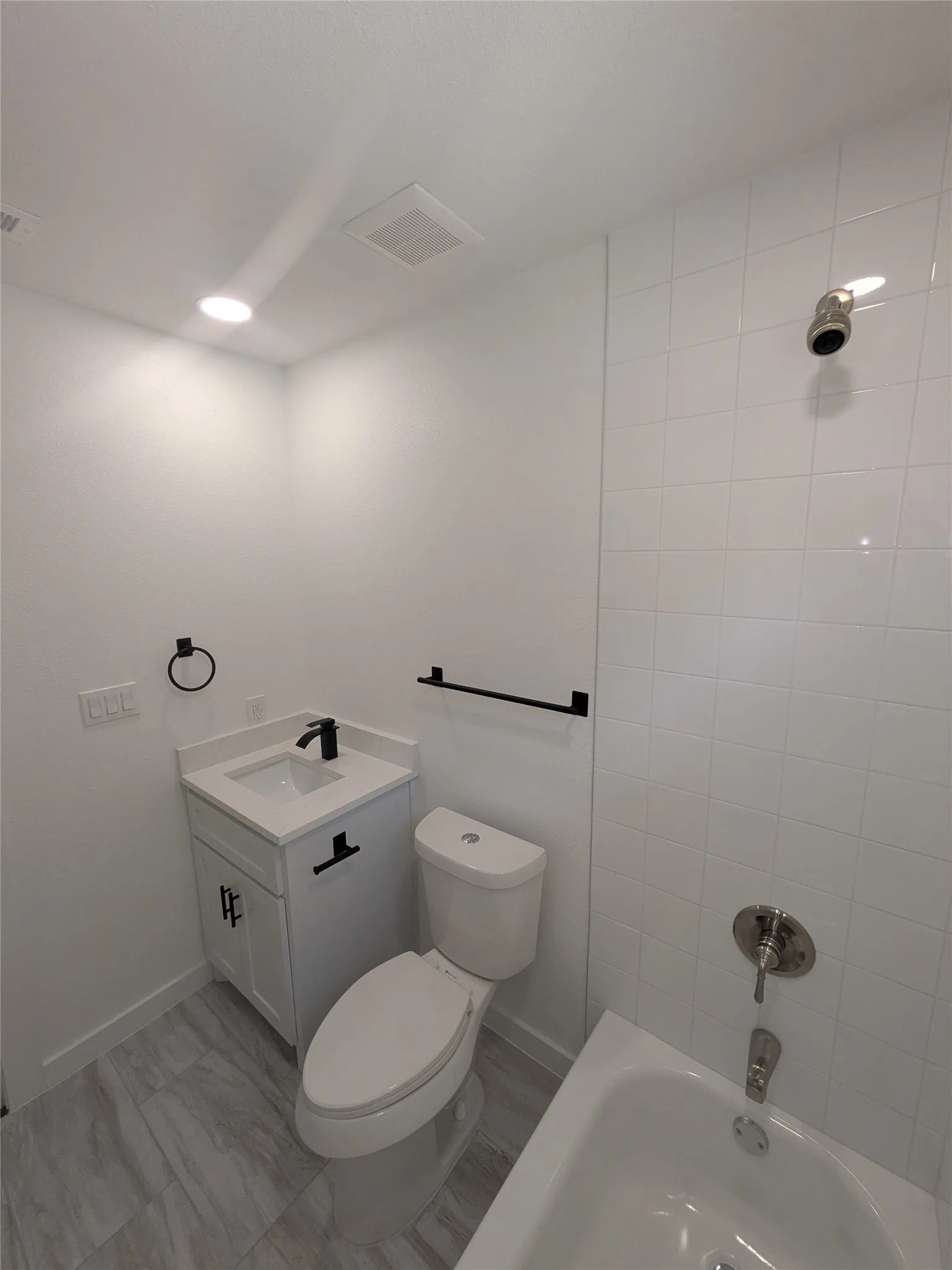 Contemporary bathroom featuring a white vanity with a quartz countertop, black hardware, and a single-handle faucet