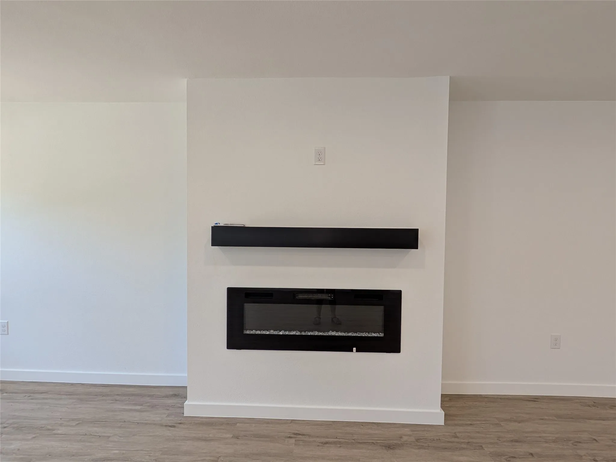Integrated wall-mounted electric fireplace with a contrasting black mantel​​‌​​​​‌​​‌‌​‌‌​​​‌‌​‌​‌​‌​​​‌​​ shelf