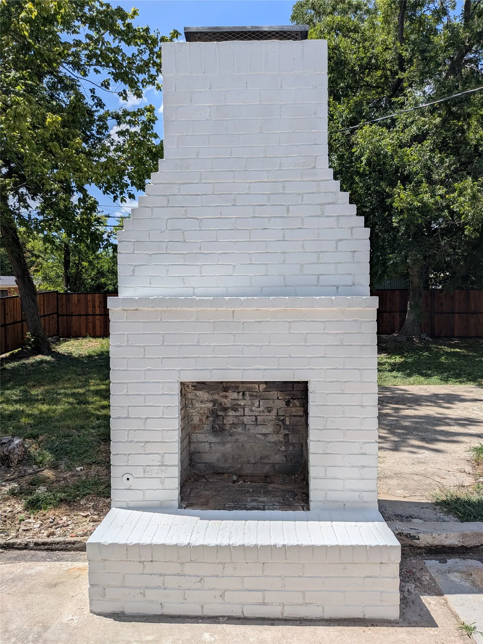 Outdoor brick fireplace with a white painted finish and a black metal chimney cap