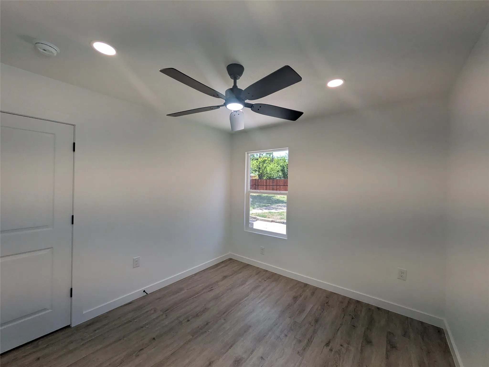 Bright room featuring wood-finish flooring, a contemporary ceiling fan, and recessed lighting
