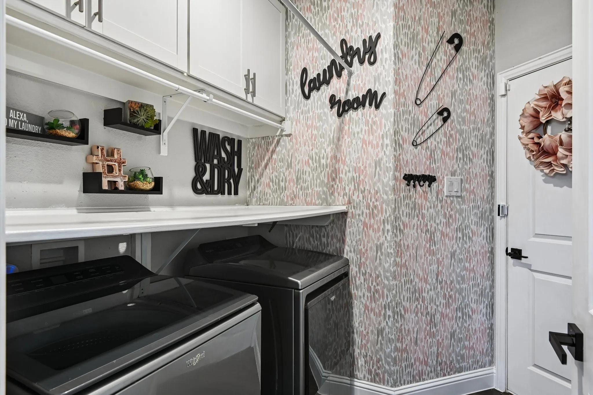 Dedicated laundry space featuring white shaker-style cabinetry, a built-in counter, and modern appliances