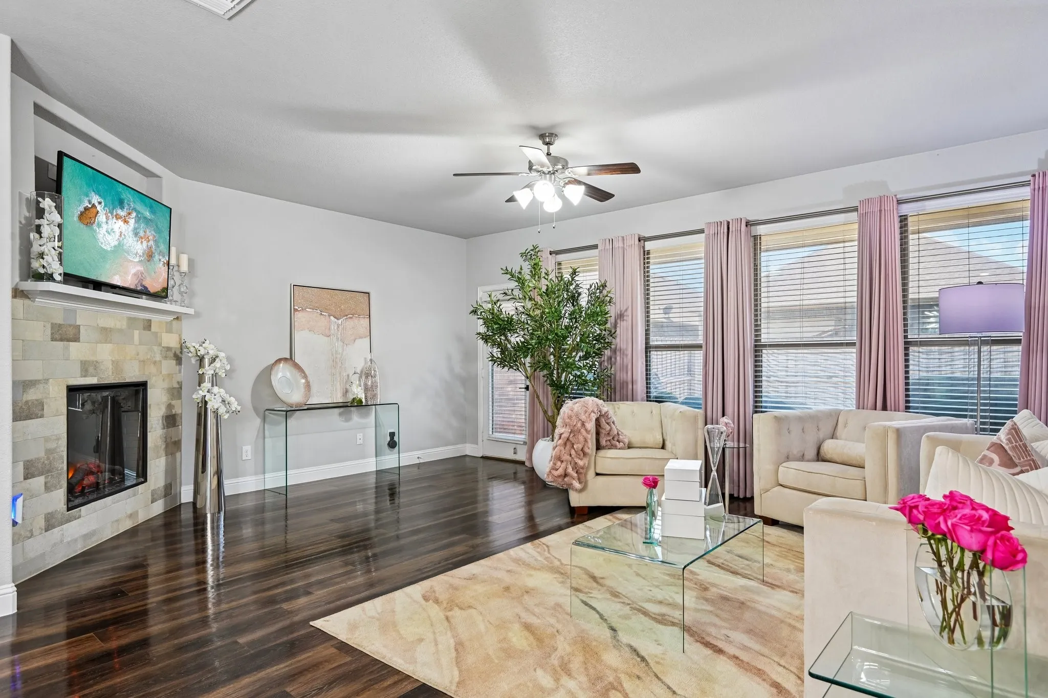 Spacious living area featuring dark wood-finish flooring and a stone-clad fireplace with mantel