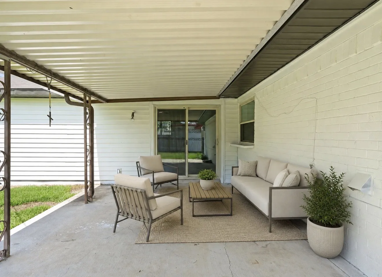 Covered patio featuring a concrete slab and white brick exterior