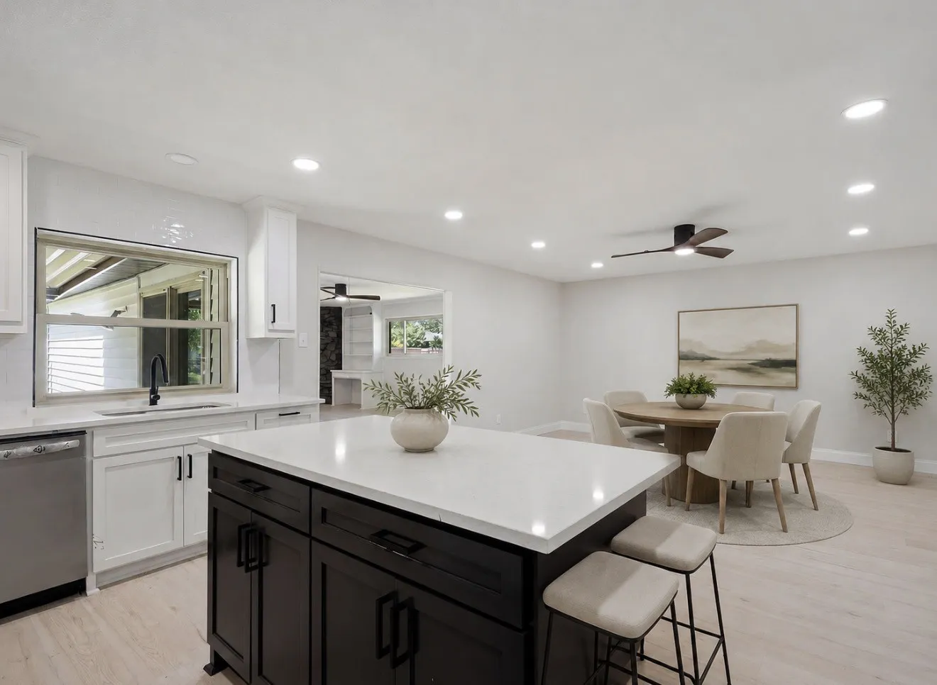 Open-concept kitchen and dining area featuring a dark wood finish island with a light-colored countertop, recessed lighting, and wood-finish flooring