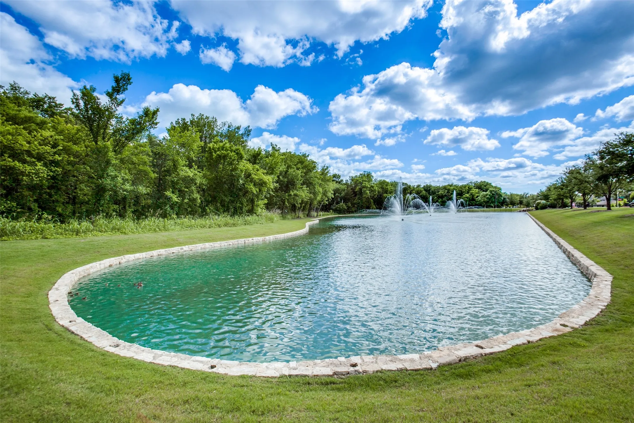 Expansive water feature with multiple fountains and a stone-lined border