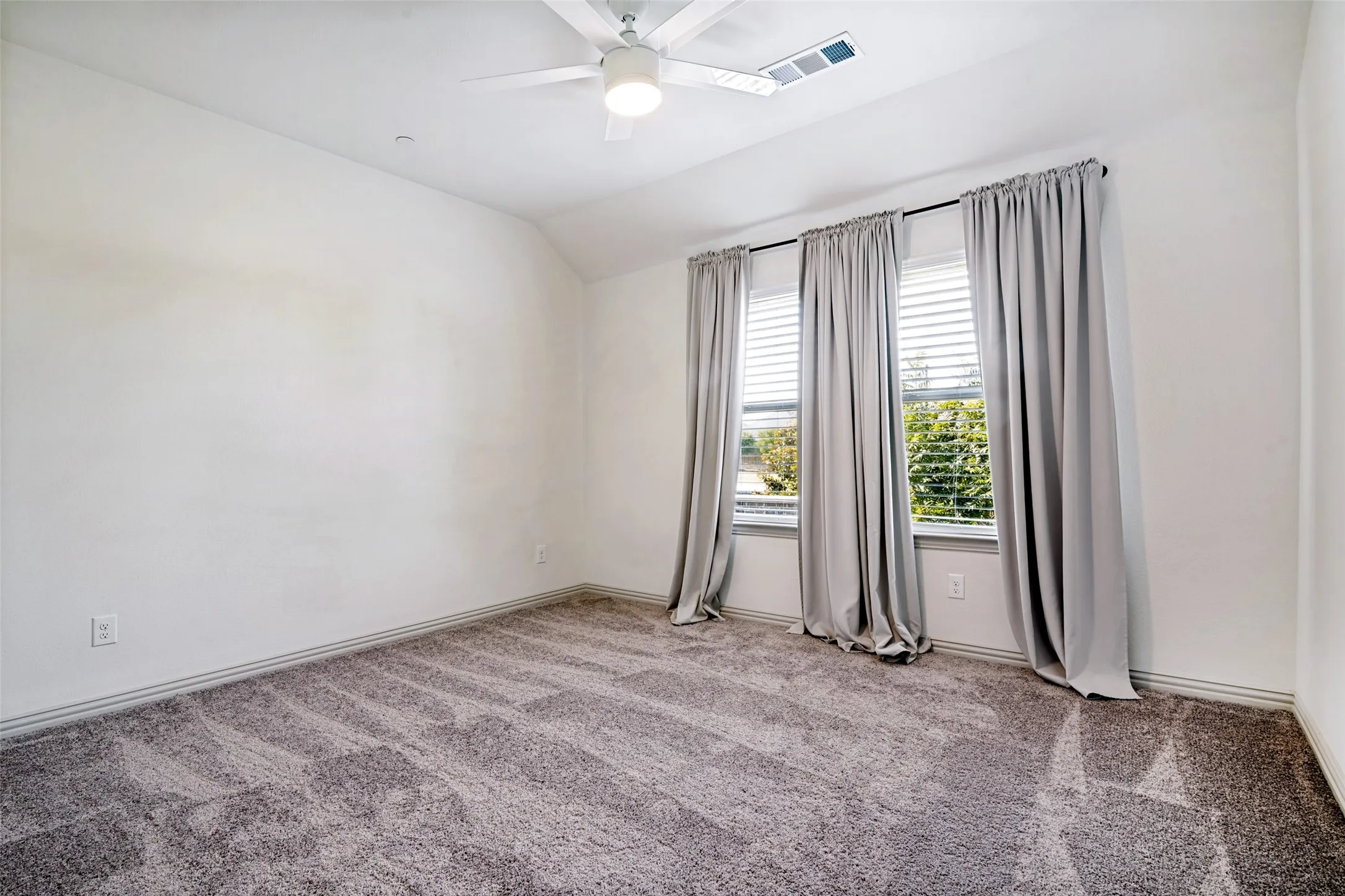 Spacious room featuring textured gray carpeting and white painted walls