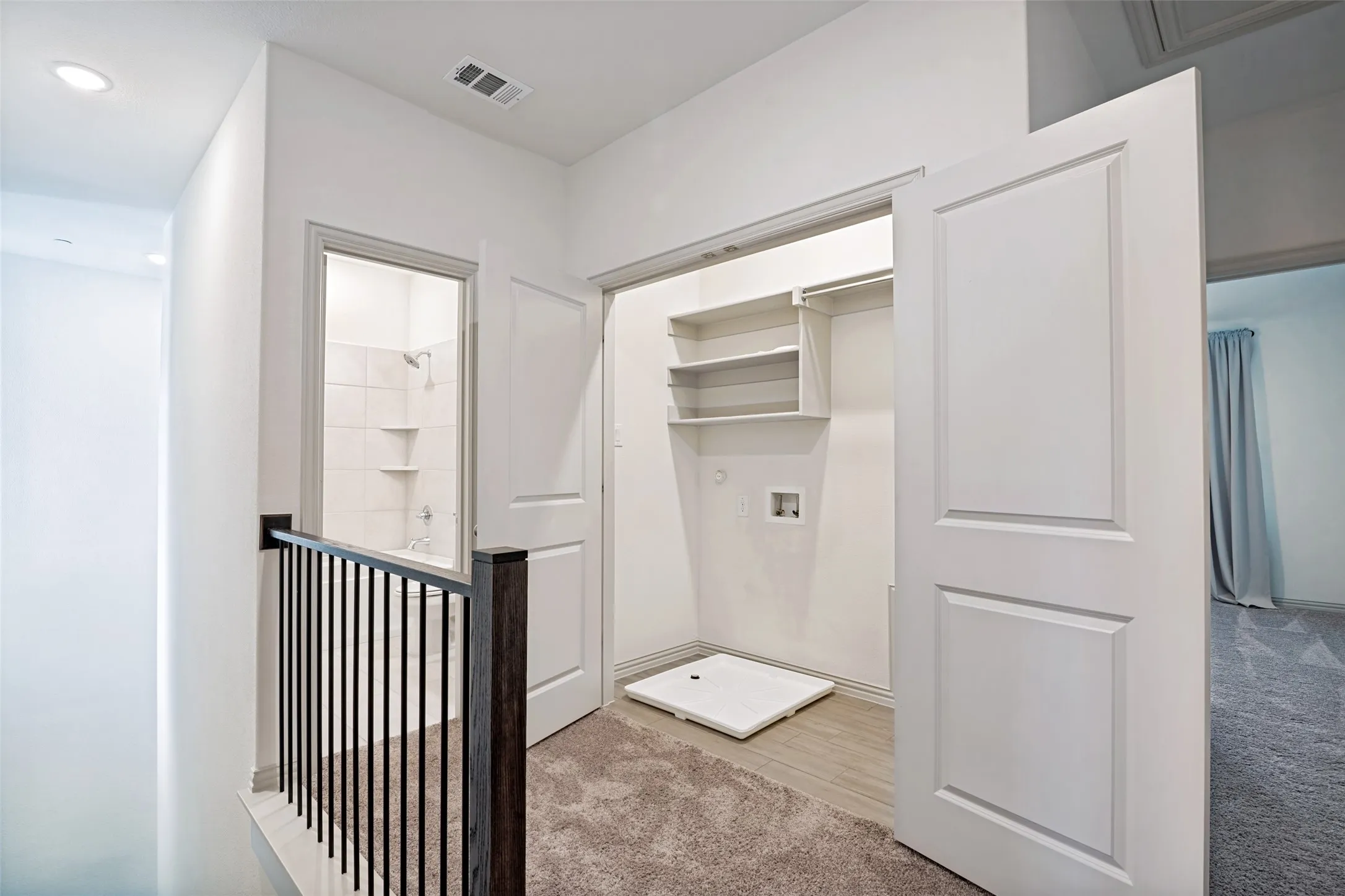 Upper-level hallway featuring a built-in laundry closet with shelving and utility hookups