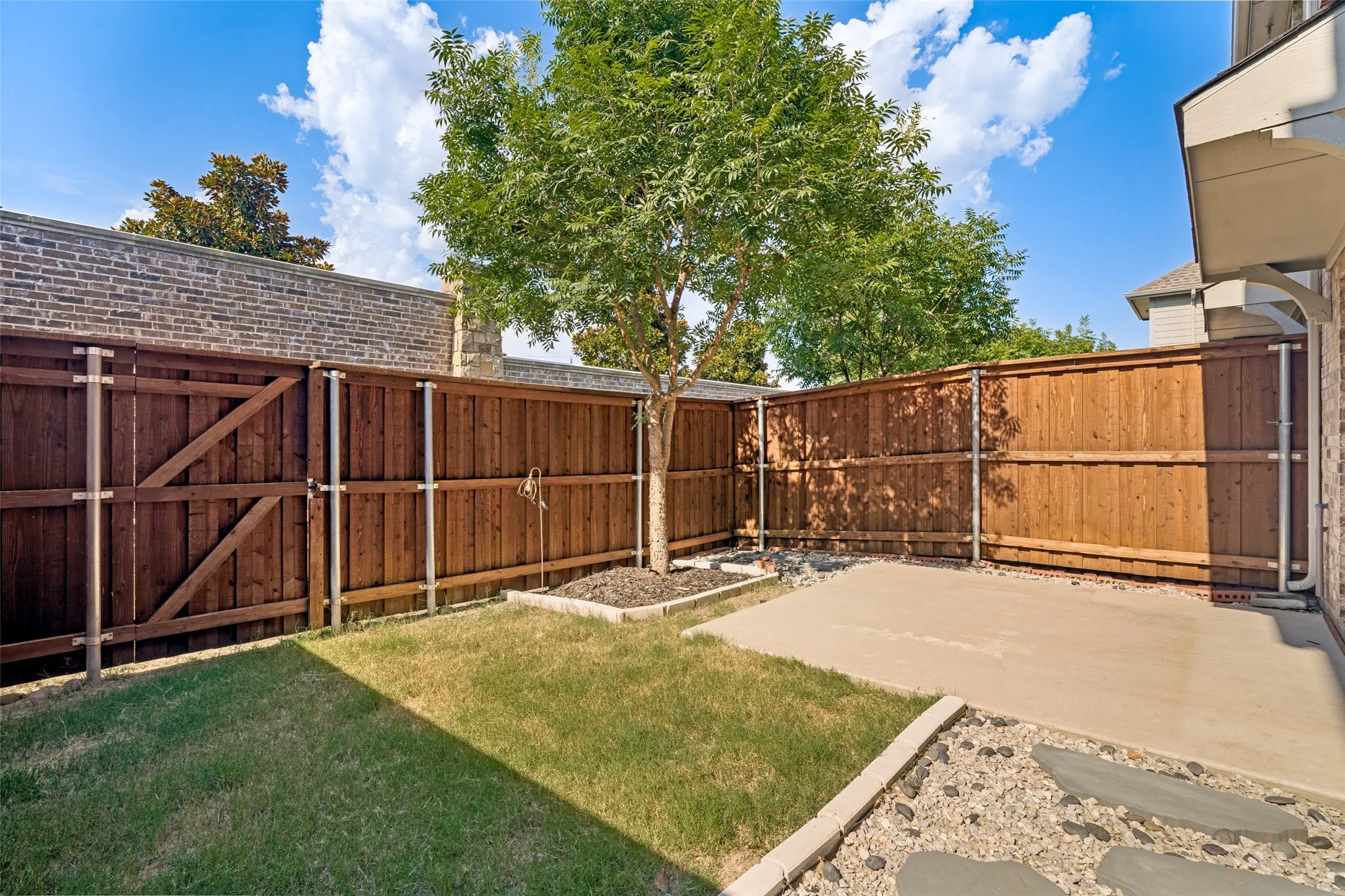Private backyard featuring a concrete patio, a grass lawn, and a mature tree