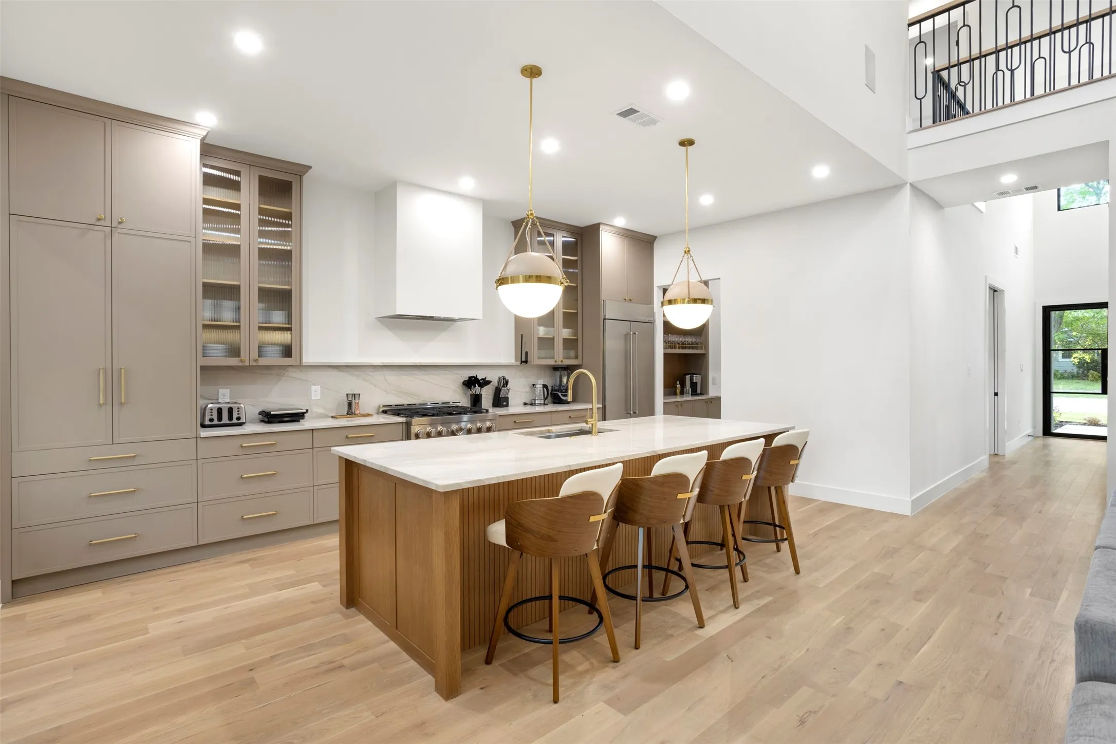 Gourmet kitchen featuring a large central island with seating, a professional-grade range, custom cabinetry, a built-in refrigerator, and wood-finish flooring