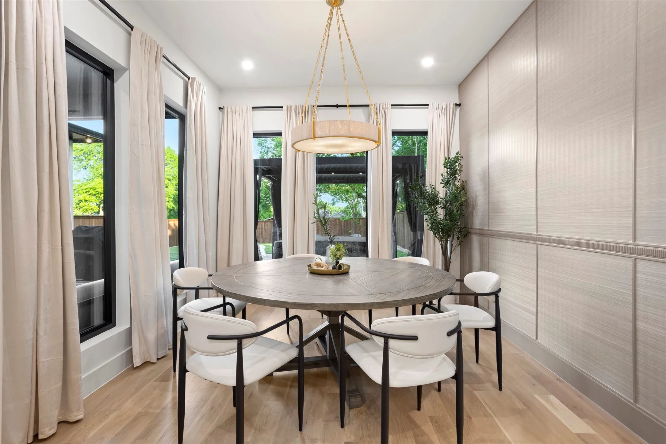 Dining space featuring wood-finish flooring, a contemporary chandelier, and a paneled accent wall