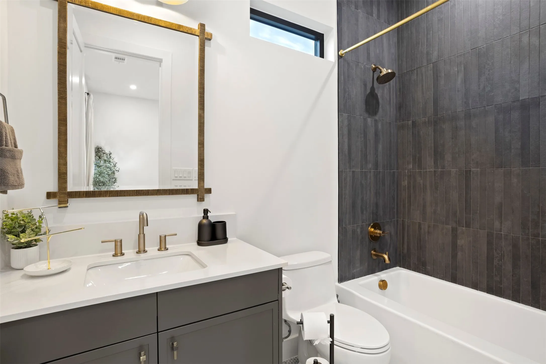 Bathroom with a white vanity featuring a rectangular undermount sink and brushed brass fixtures, complemented by a white countertop