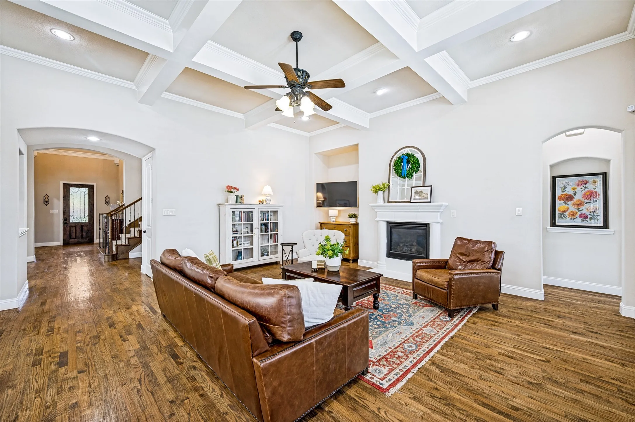 Gas fireplace and wood flooring. Archway leads into the primary bedroom.