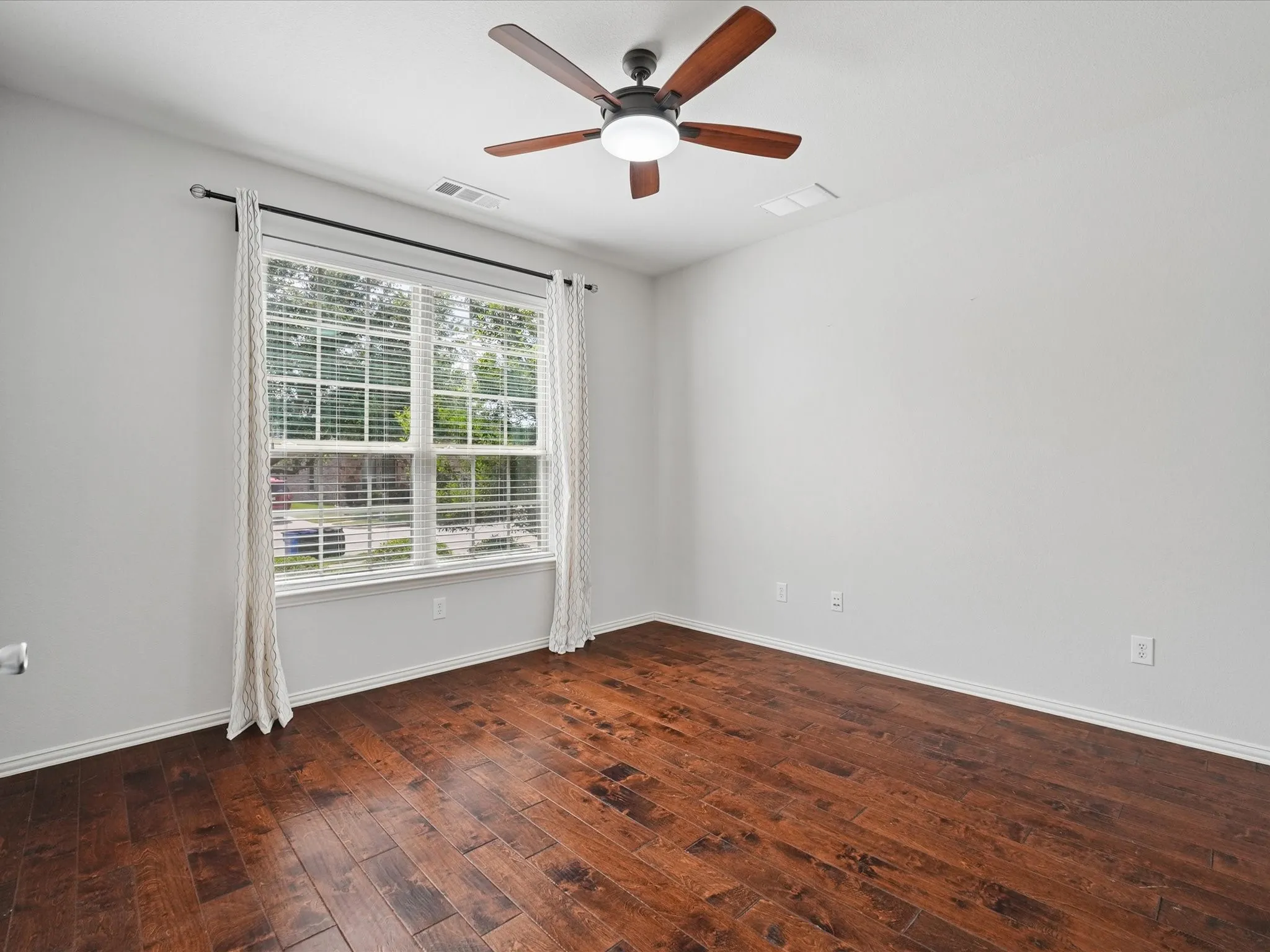 Interior room featuring rich wood-finish flooring and a ceiling fan with integrated lighting