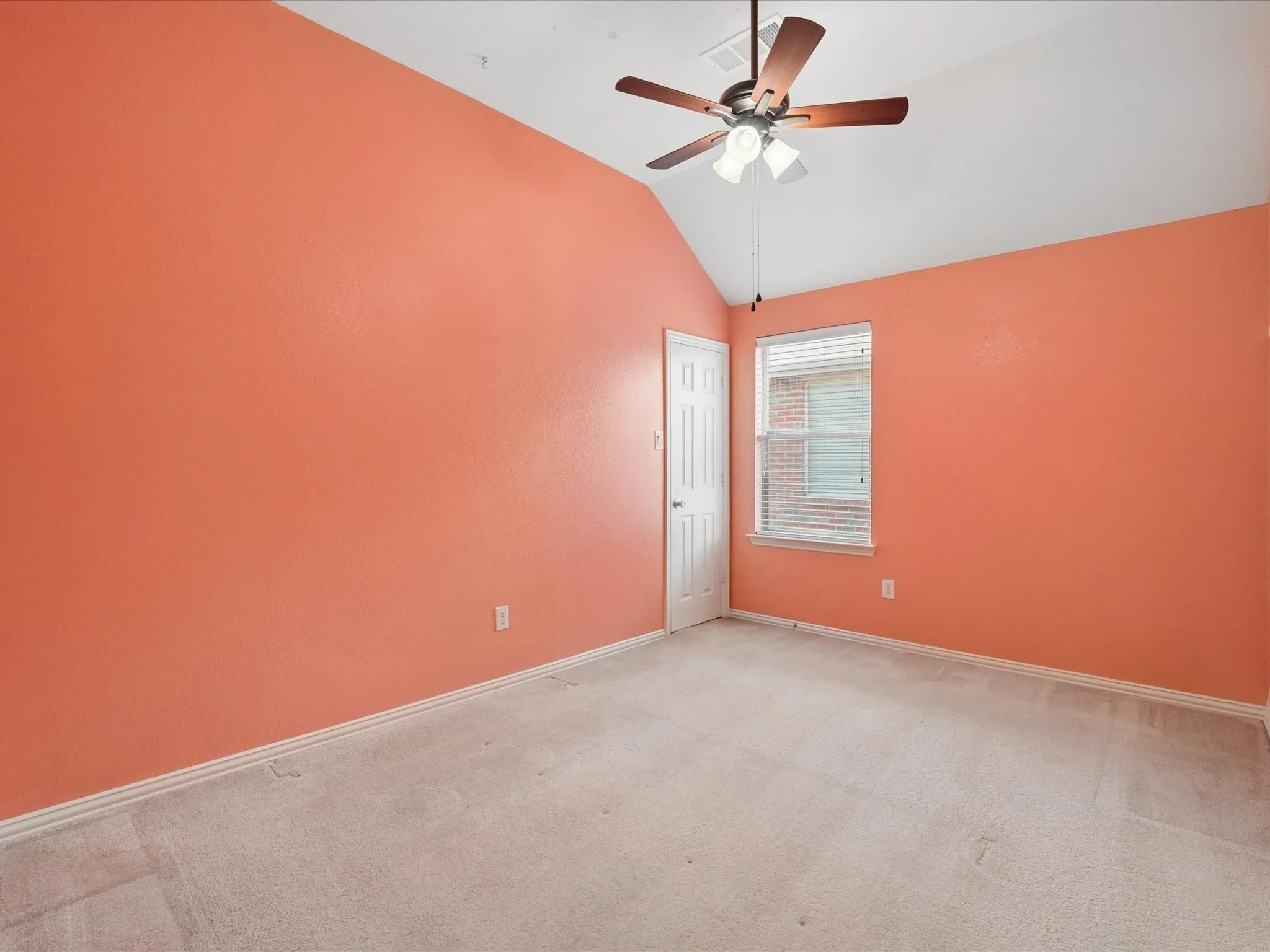 Spacious room featuring vaulted ceilings and a ceiling fan with light fixture