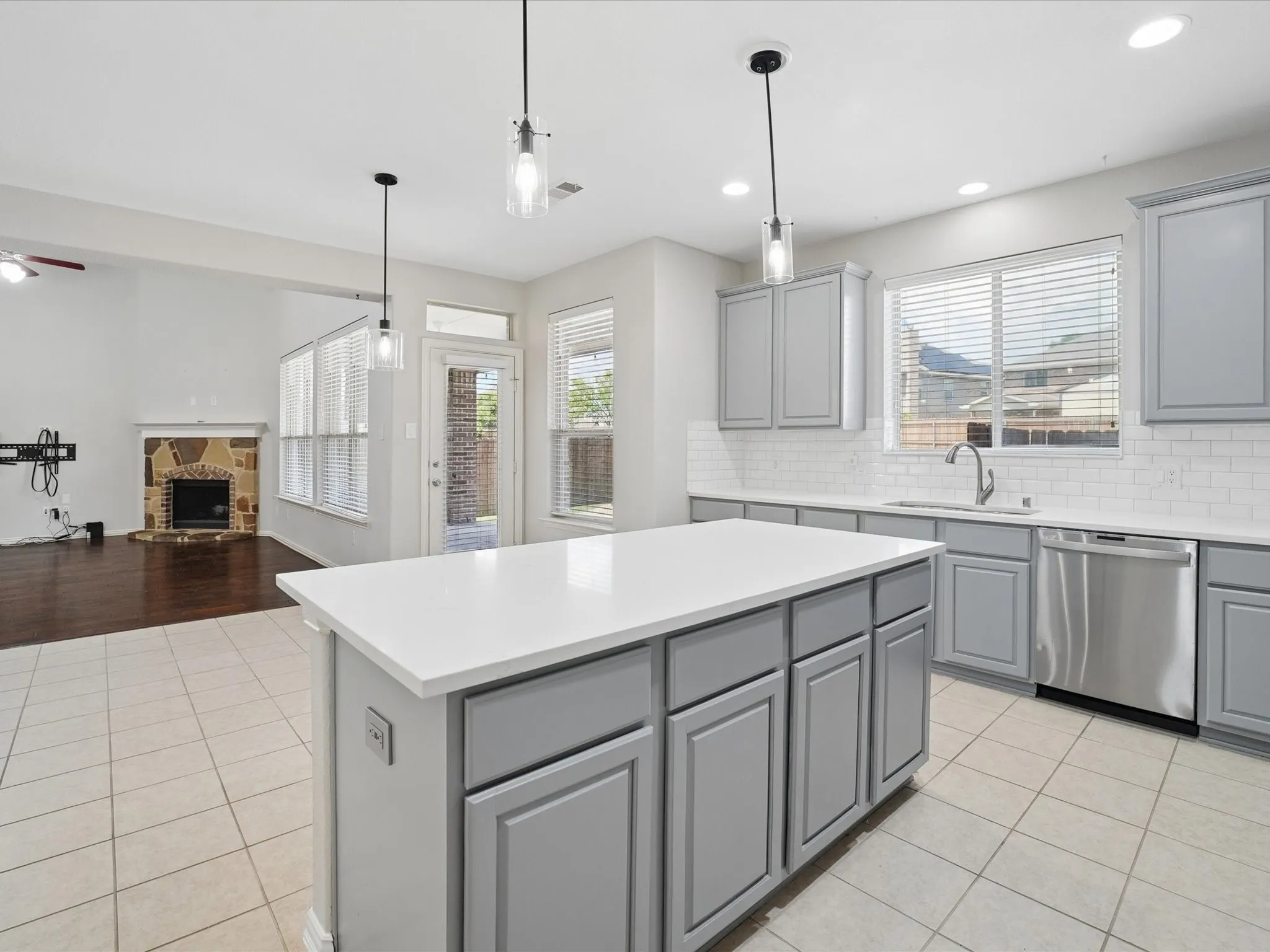 Kitchen with light gray cabinetry, white subway tile backsplash, white countertops, and stainless steel appliances
