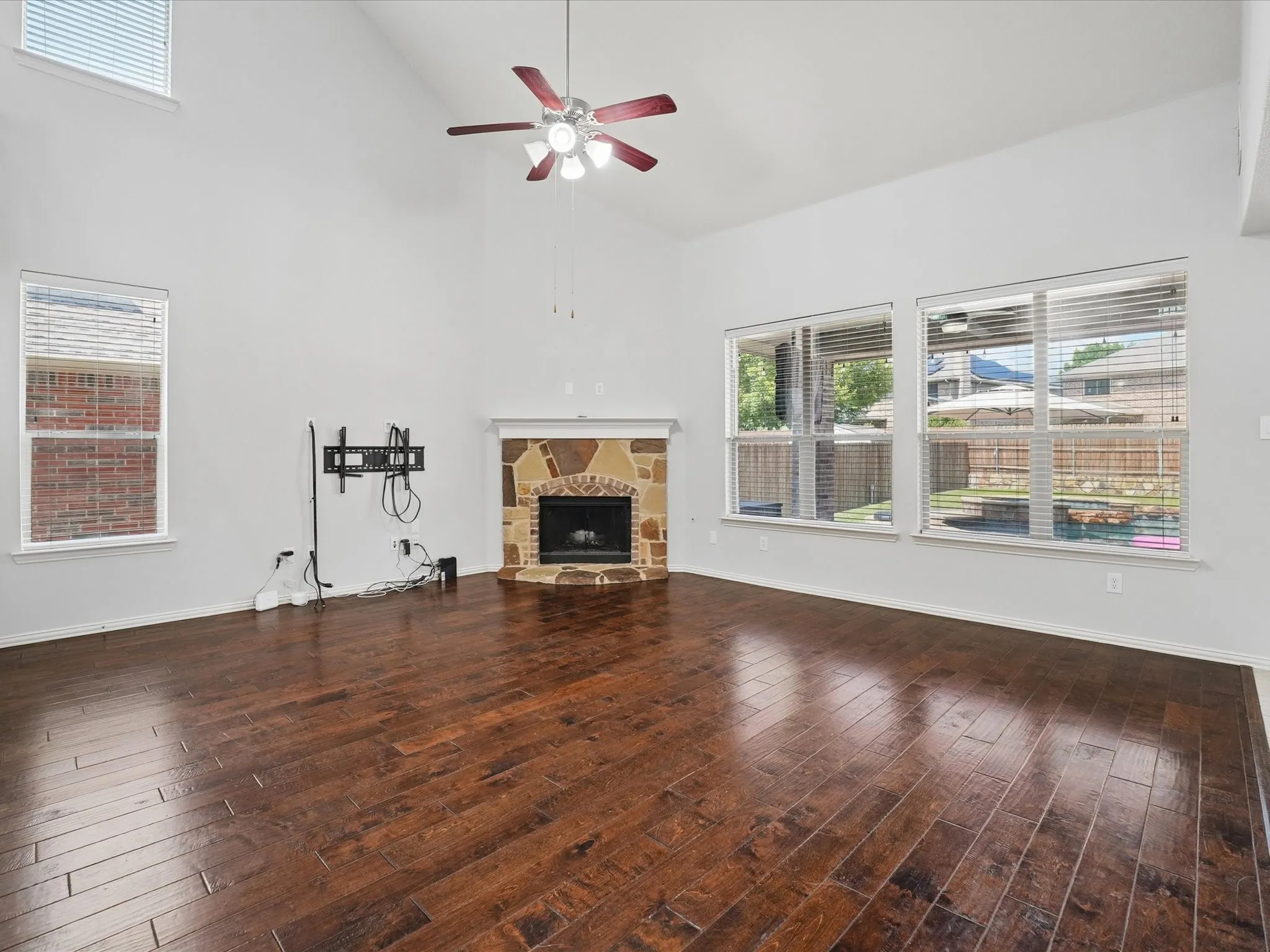 Spacious interior with vaulted ceilings, dark wood-finish flooring, and a corner stone-front fireplace