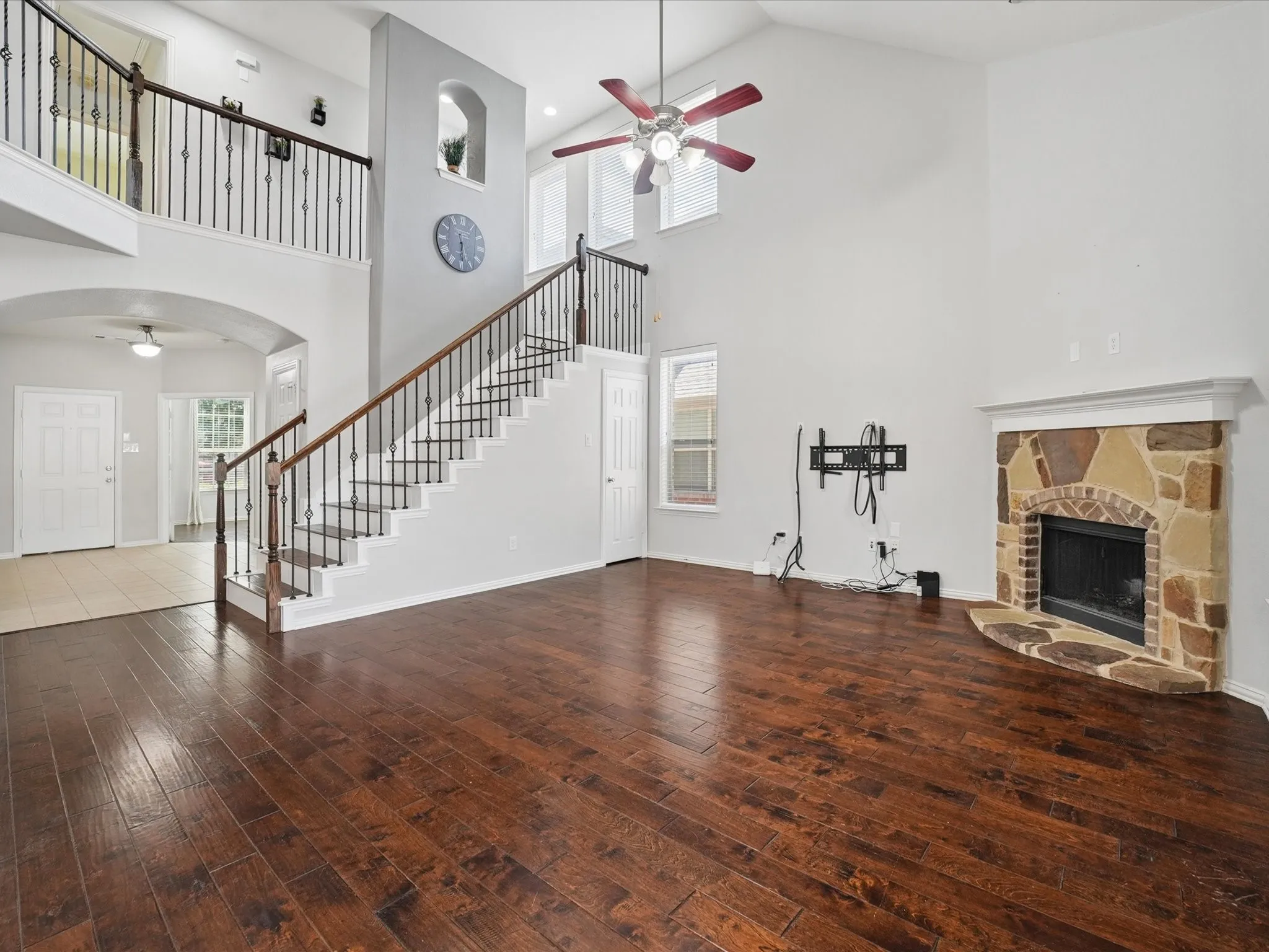 Two-story living area featuring wood-finish flooring and a stone-faced fireplace with a brick firebox