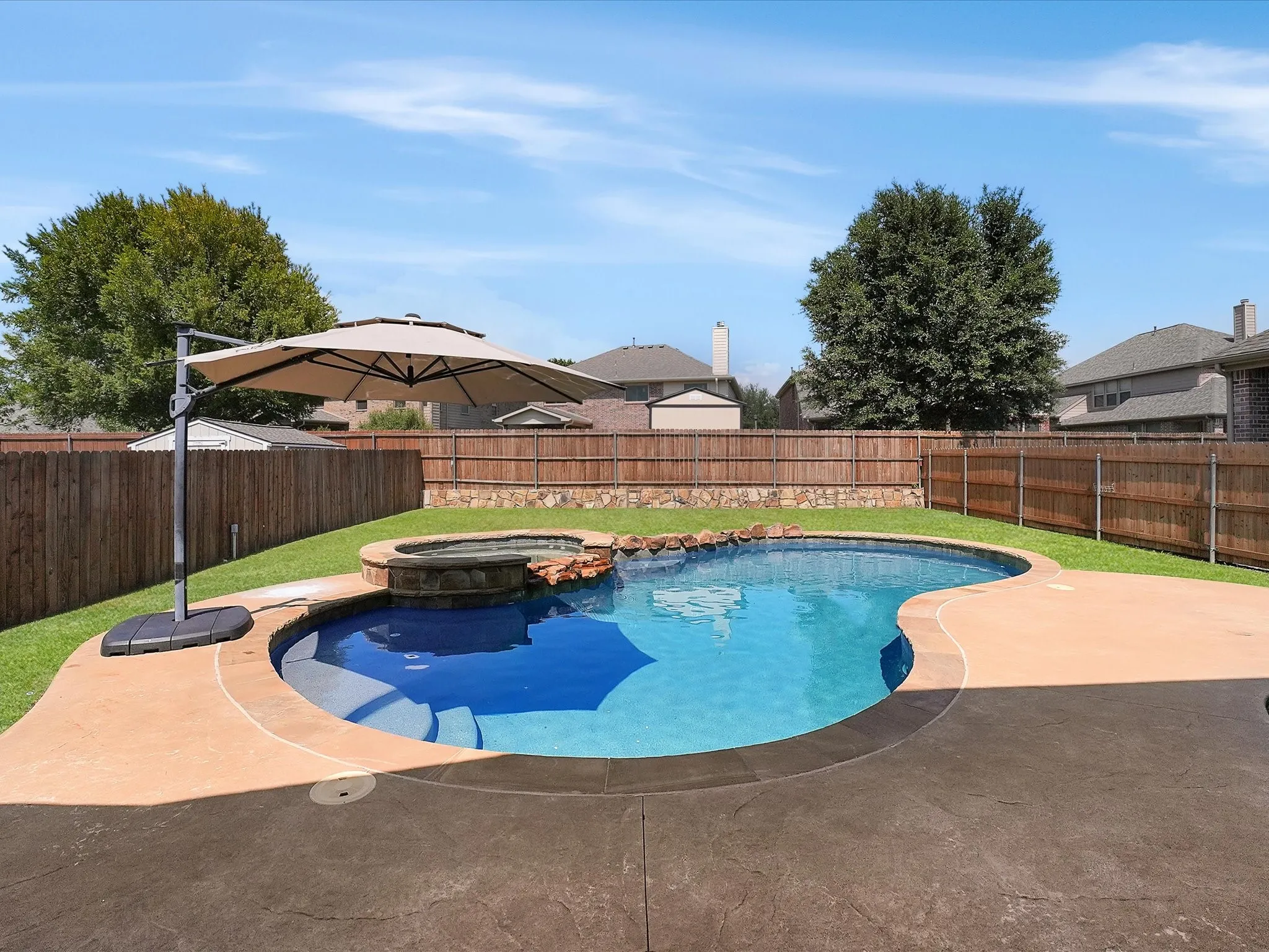 Backyard featuring a freeform swimming pool with integrated spa and rock waterfall