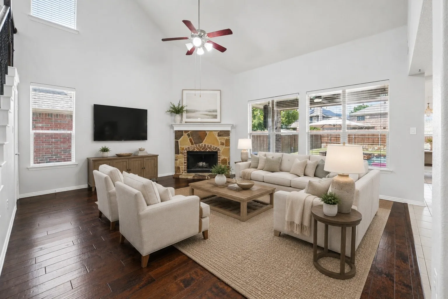 Spacious living area featuring high vaulted ceilings, wood-finish flooring, and a stone-clad fireplace