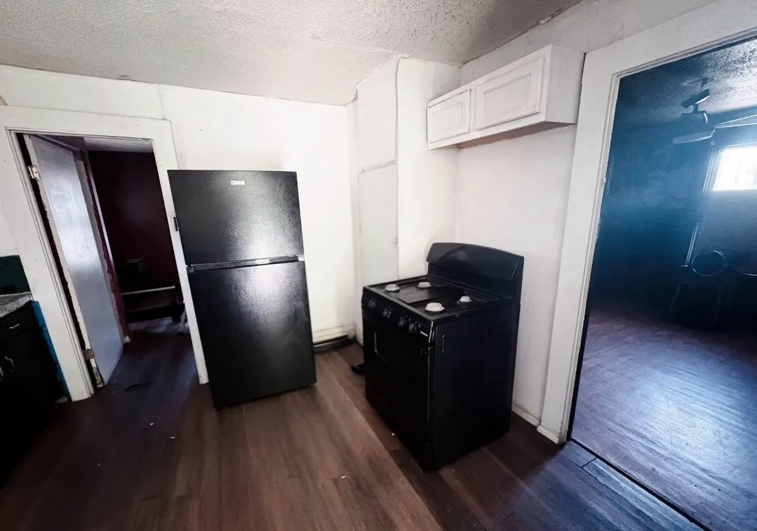 Kitchen area featuring dark-finish flooring, white walls, and white upper cabinetry