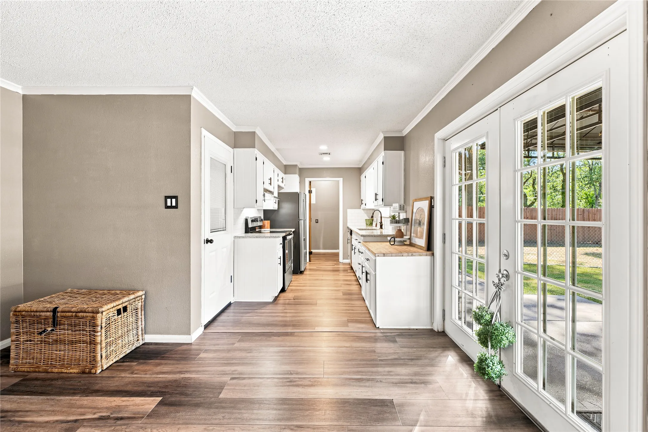 Galley kitchen featuring white cabinetry, light countertops, wood-finish flooring, and stainless steel appliances