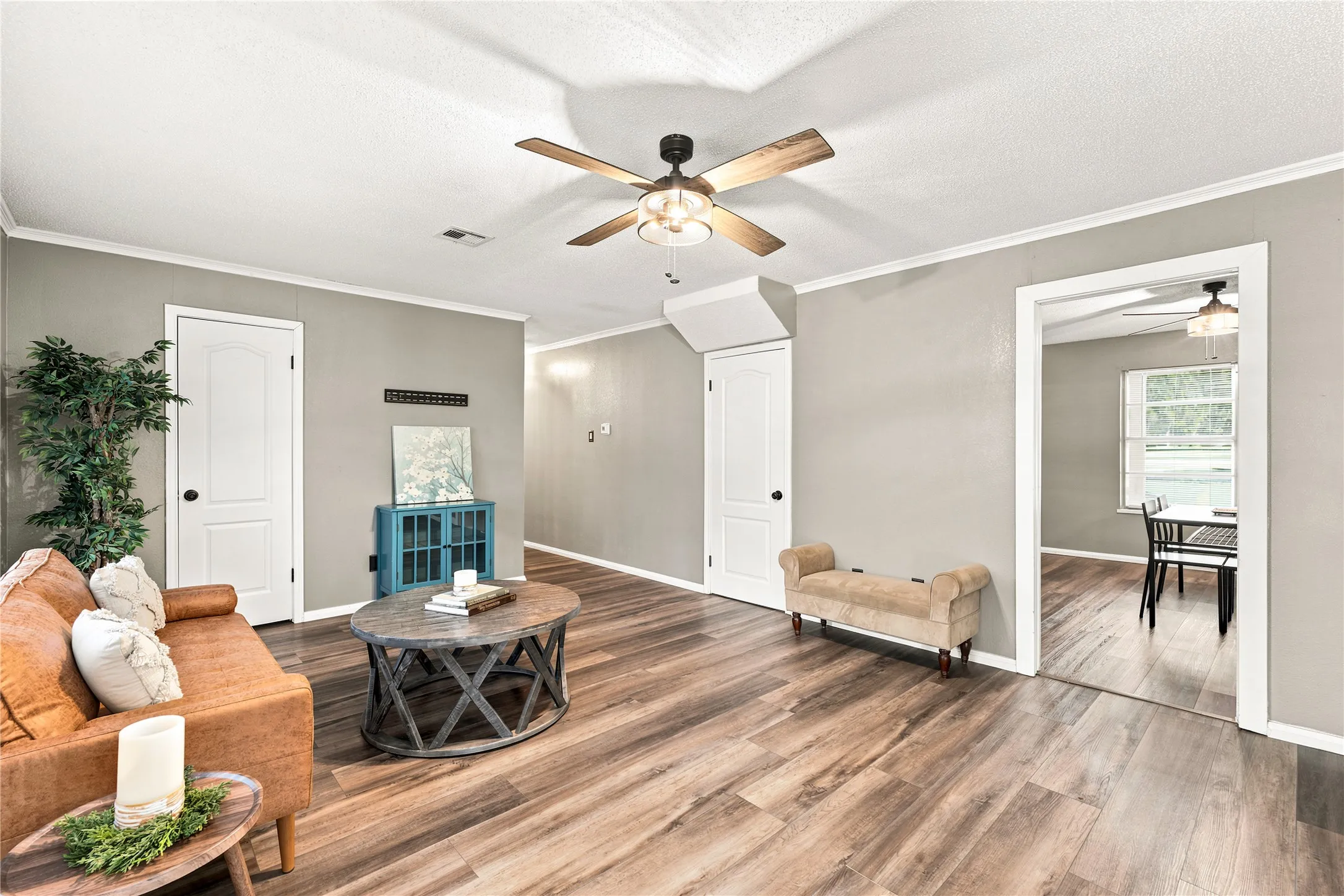 Spacious living area featuring wood-finish flooring, light gray wall paint, and crisp white trim