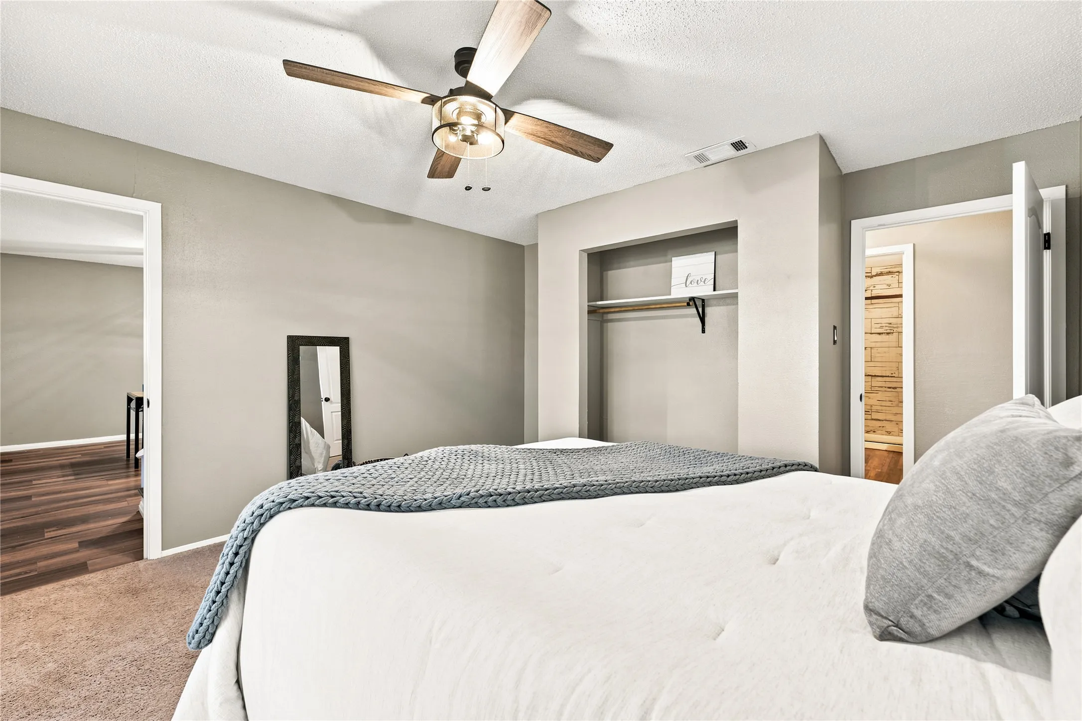 Bedroom featuring a ceiling fan with integrated lighting, a built-in open closet with shelving and hanging rod, neutral wall finishes, and carpet flooring
