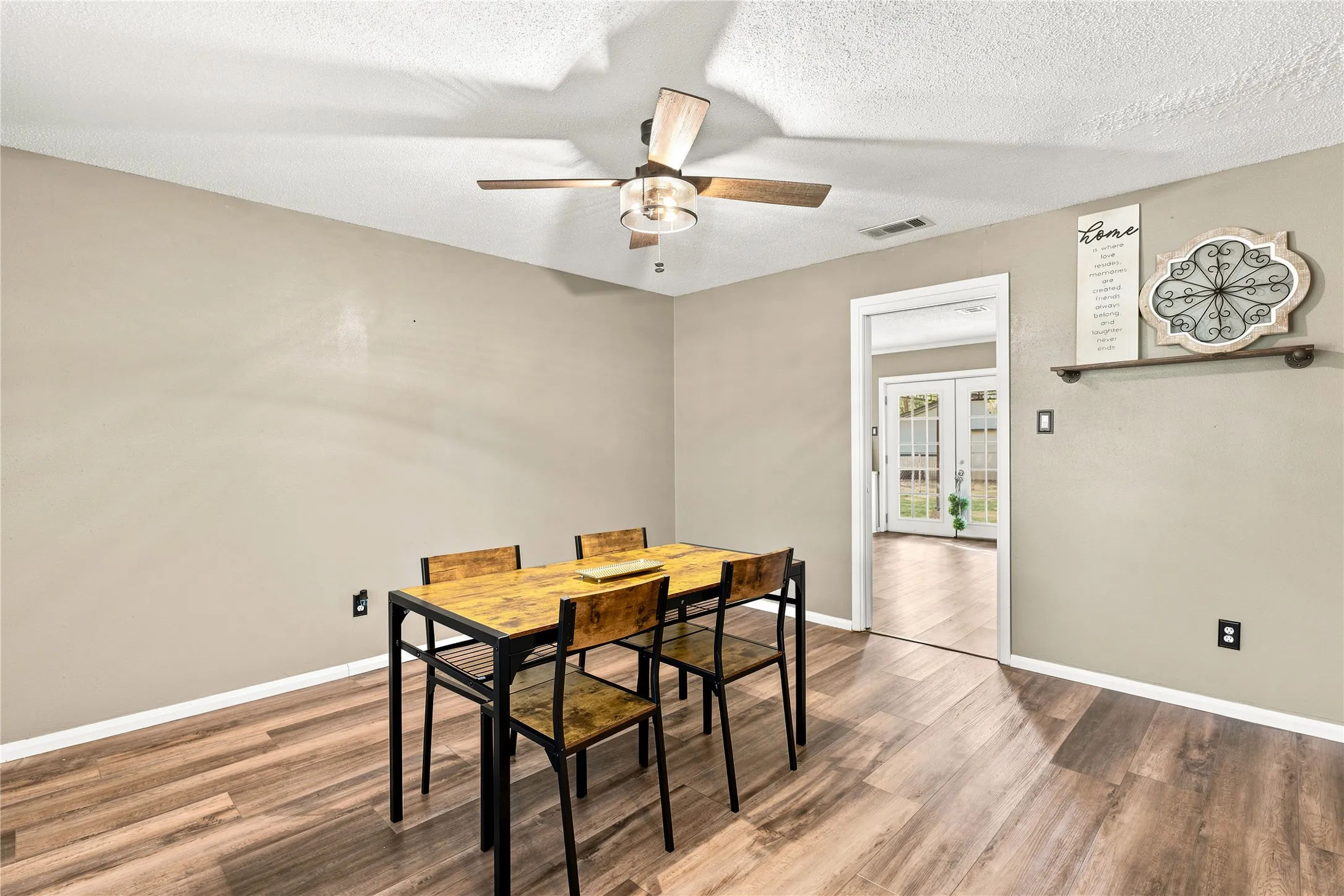 Open dining area featuring wood-finish flooring, neutral-toned walls, and a ceiling fan with integrated lighting