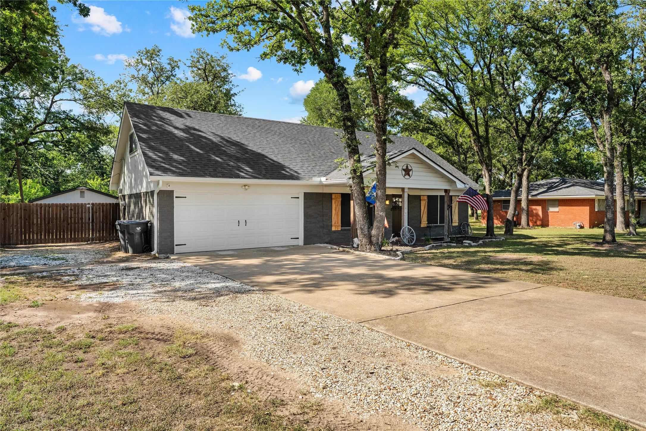 Exterior featuring a two-car garage, dark-colored brick facade, light-colored siding, and a dark shingled​​‌​​​​‌​​‌‌​‌‌​​​‌‌​‌​‌​‌​​​‌​​ roof