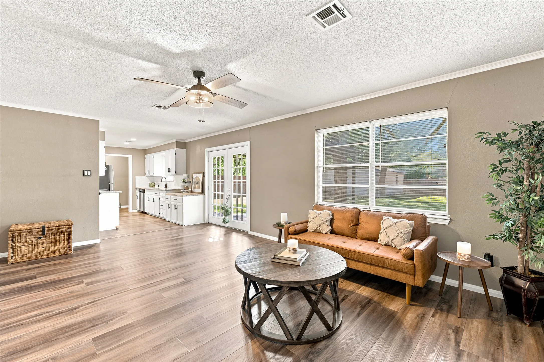 Spacious interior featuring wood-finish flooring, neutral paint palette, ceiling fan with integrated lighting, and white trim