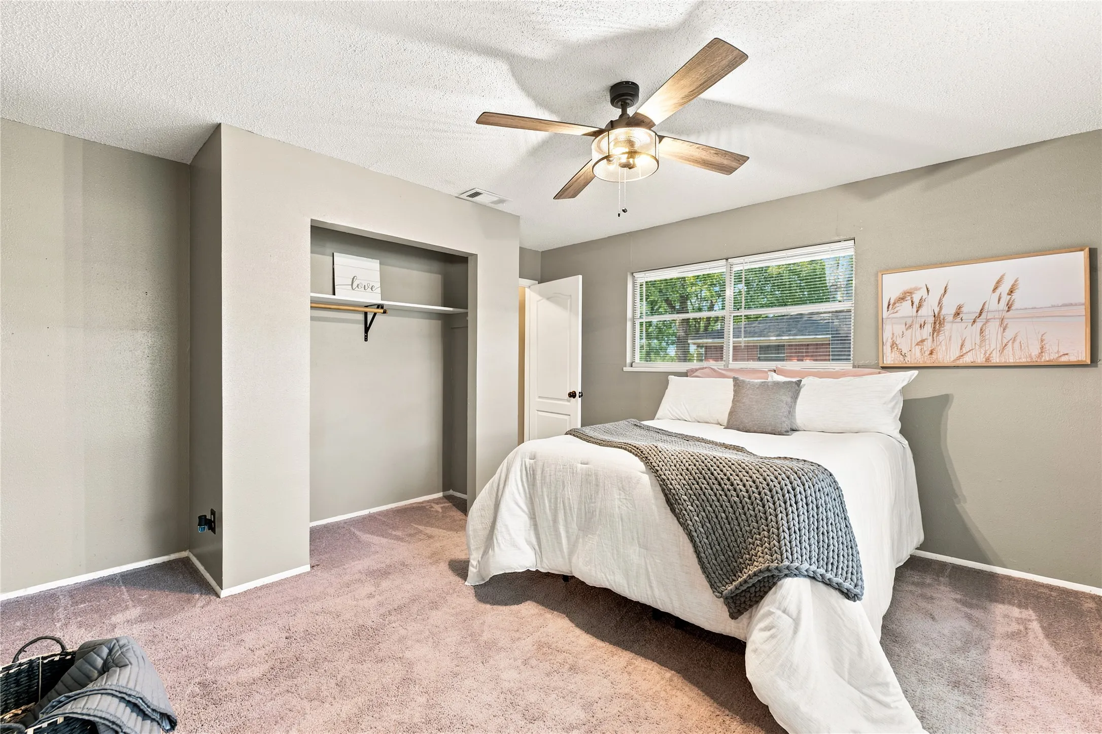 Bedroom featuring neutral wall paint, a ceiling fan with light fixture, dual windows, and an open closet with shelving