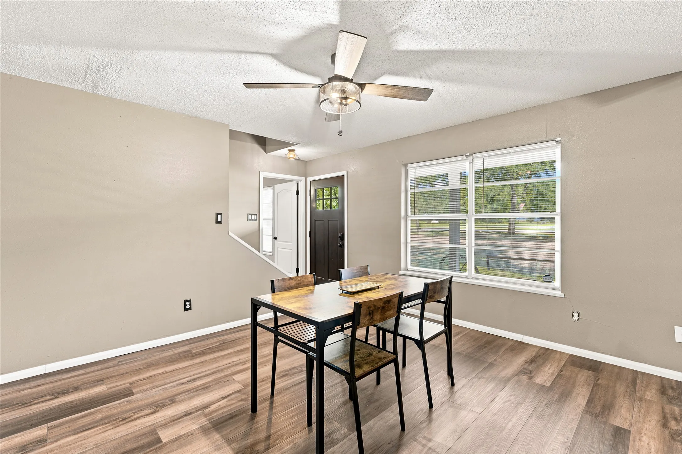 Interior space featuring wood-finish flooring, neutral wall tones, and a ceiling fan with integrated lighting