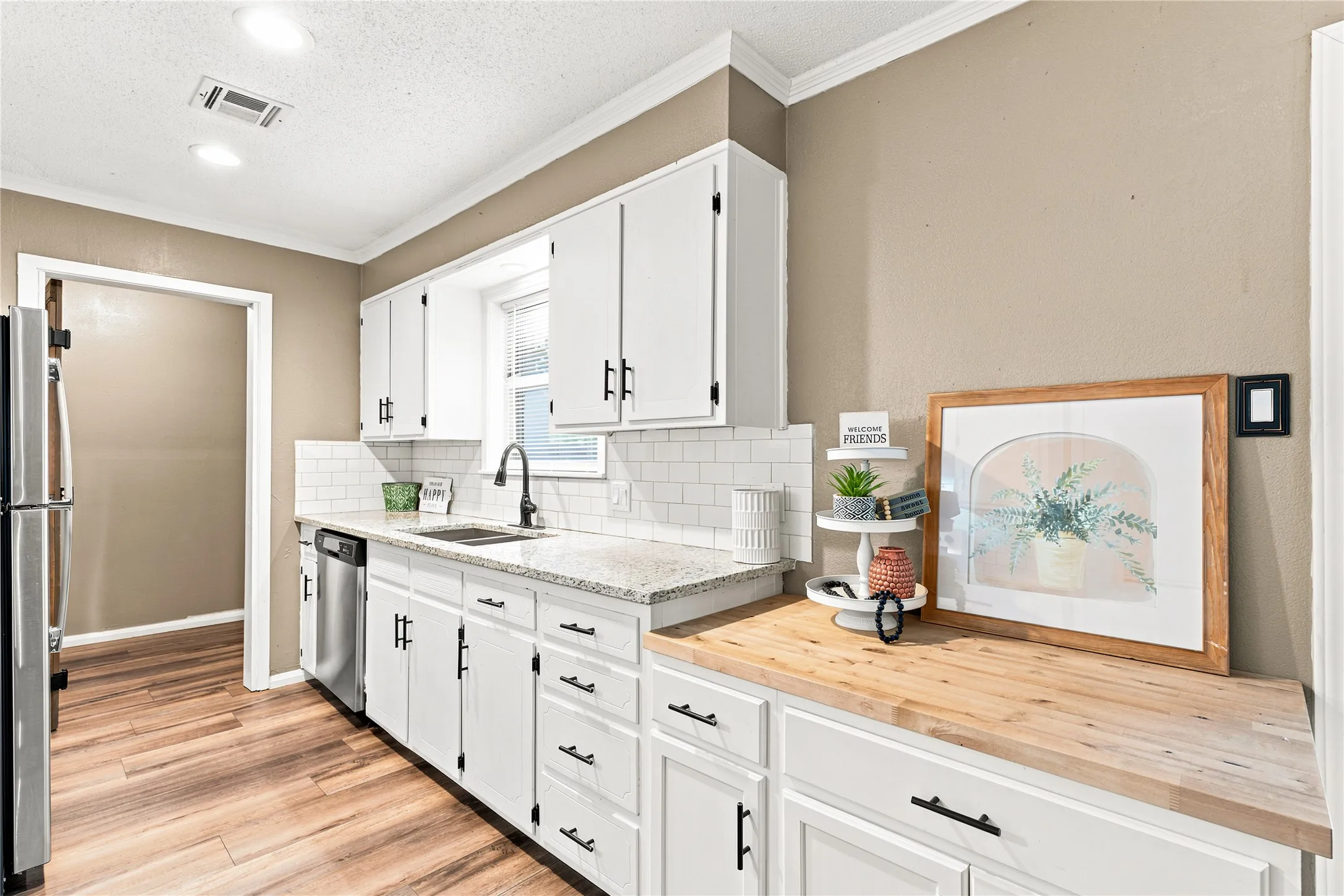 Modern kitchen featuring white cabinetry with matte black hardware, a subway tile backsplash, and light-toned countertops
