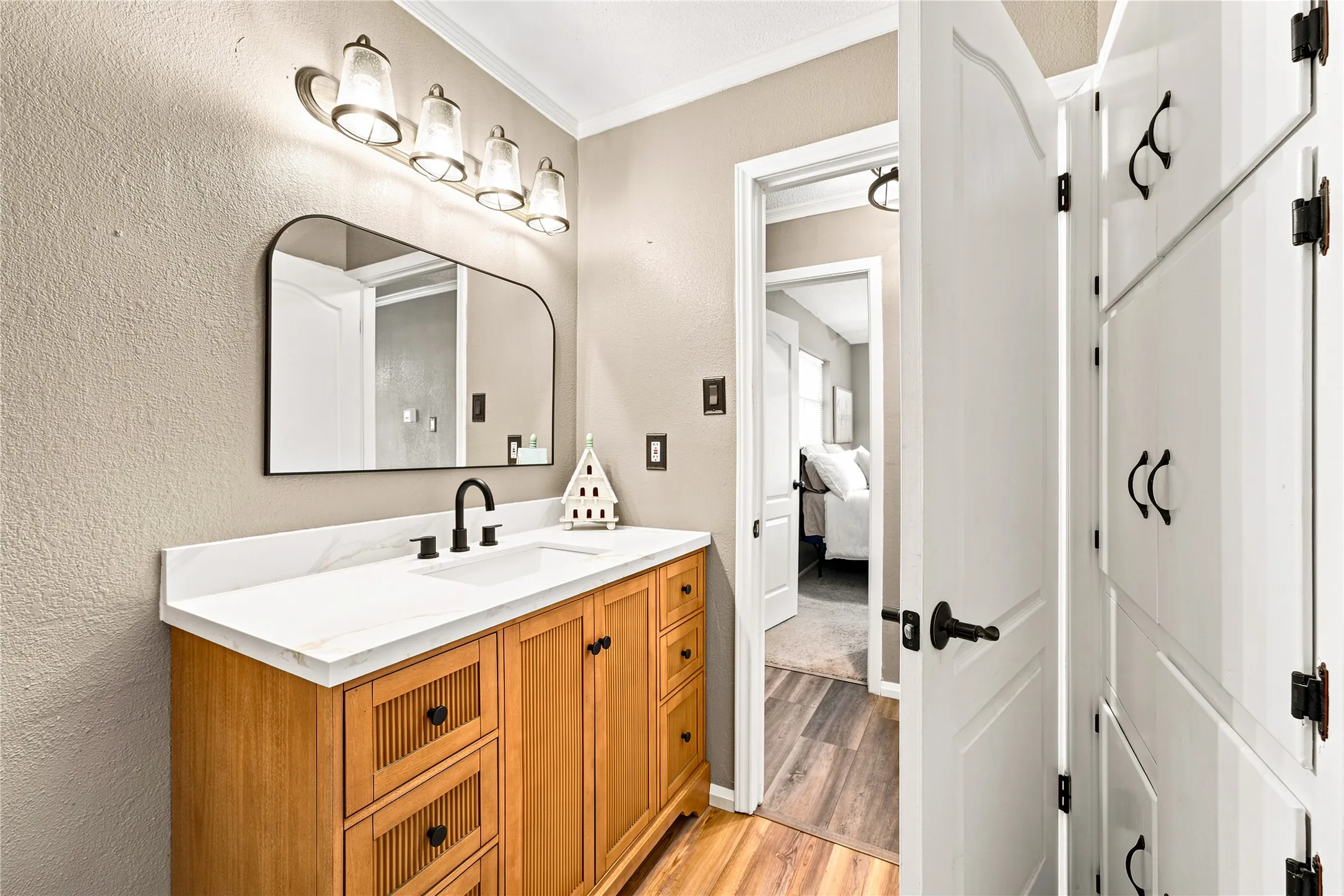Bathroom featuring a wood-finish vanity with a white countertop, an undermount sink, and a black faucet