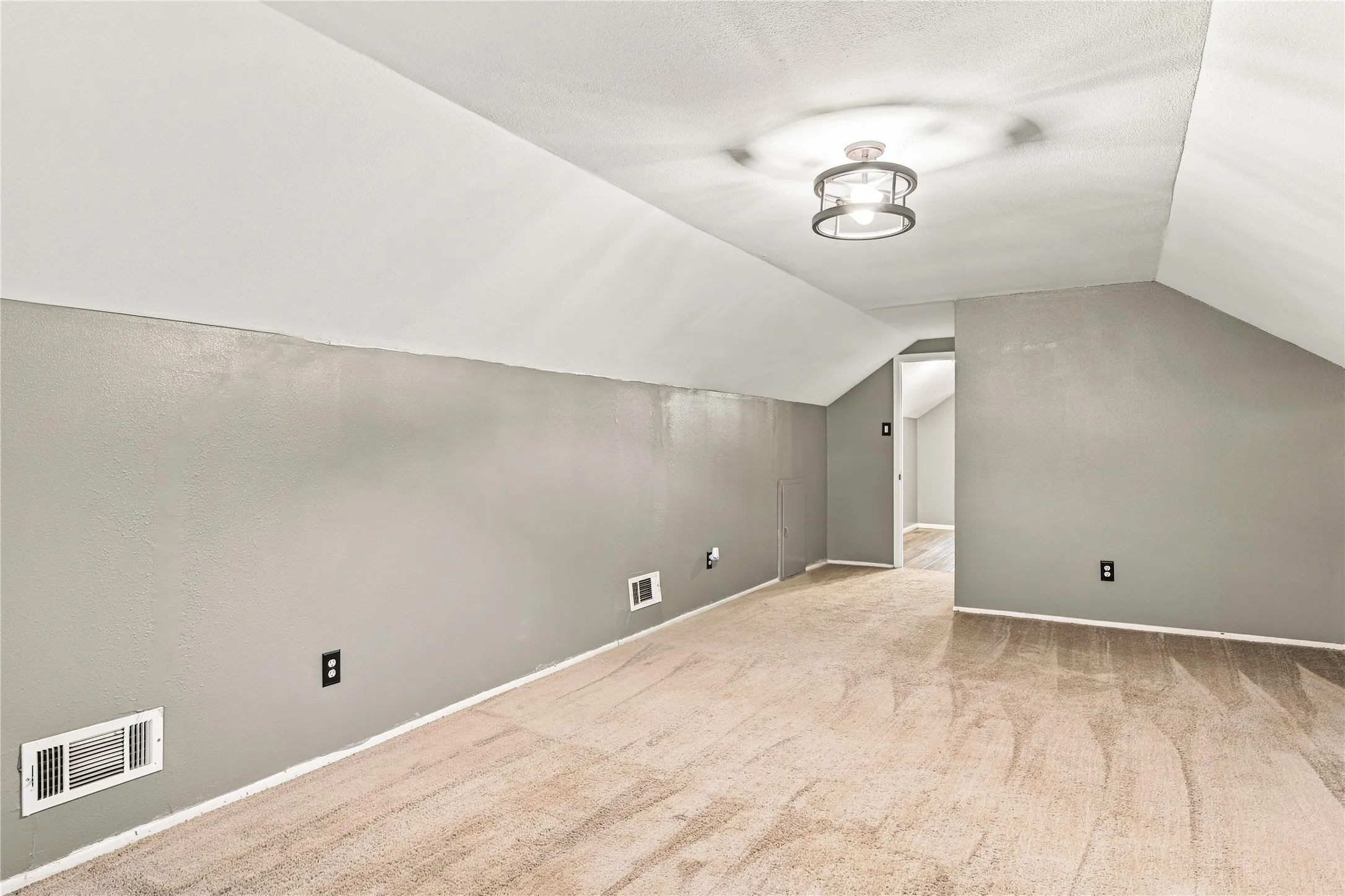 Spacious room featuring vaulted ceilings, light-toned carpeting, and a modern semi-flush mount ceiling fixture