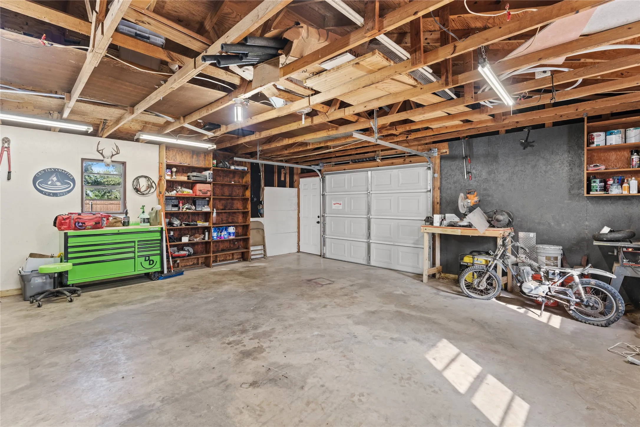 Spacious garage with exposed wood beam ceiling and concrete flooring